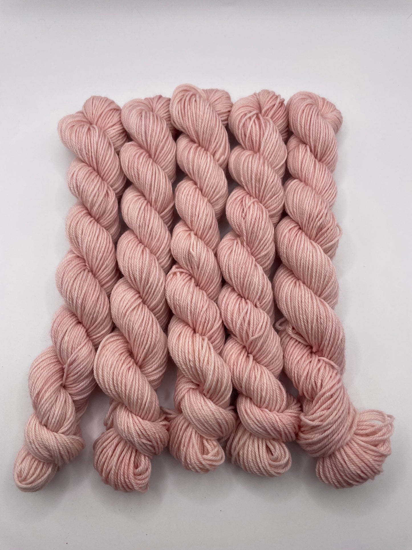 Pale pink yarn mini skeins on a white background