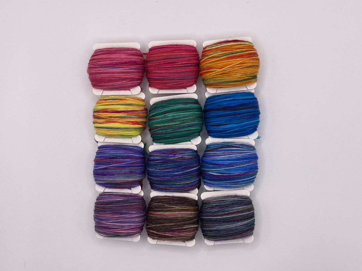 12 yarn bobbins in a rainbow of colours
