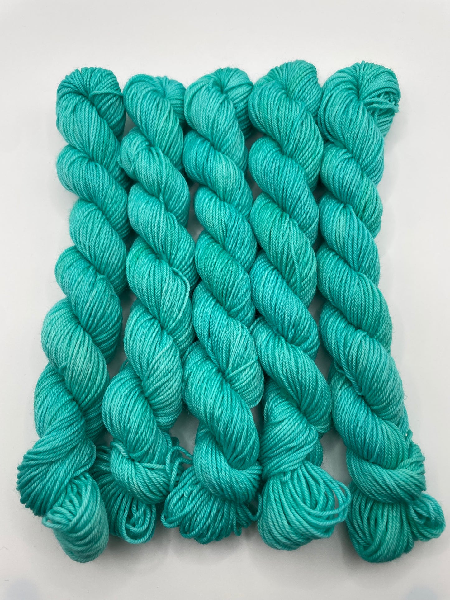Teal yarn mini skeins on a white background