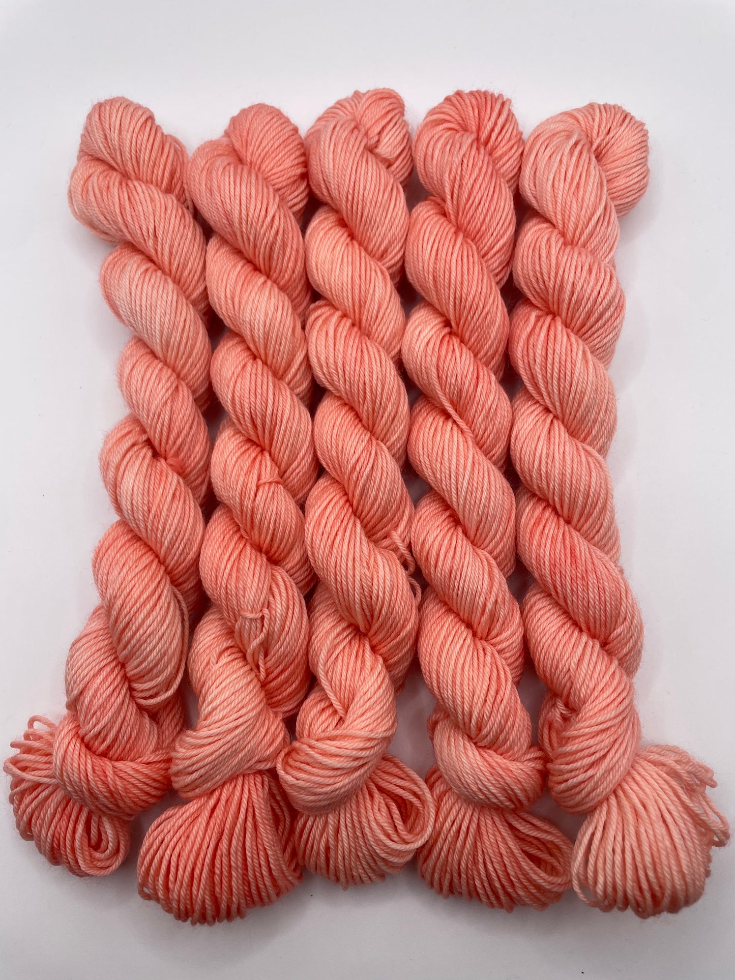Peachy coral yarn mini skeins on a white background