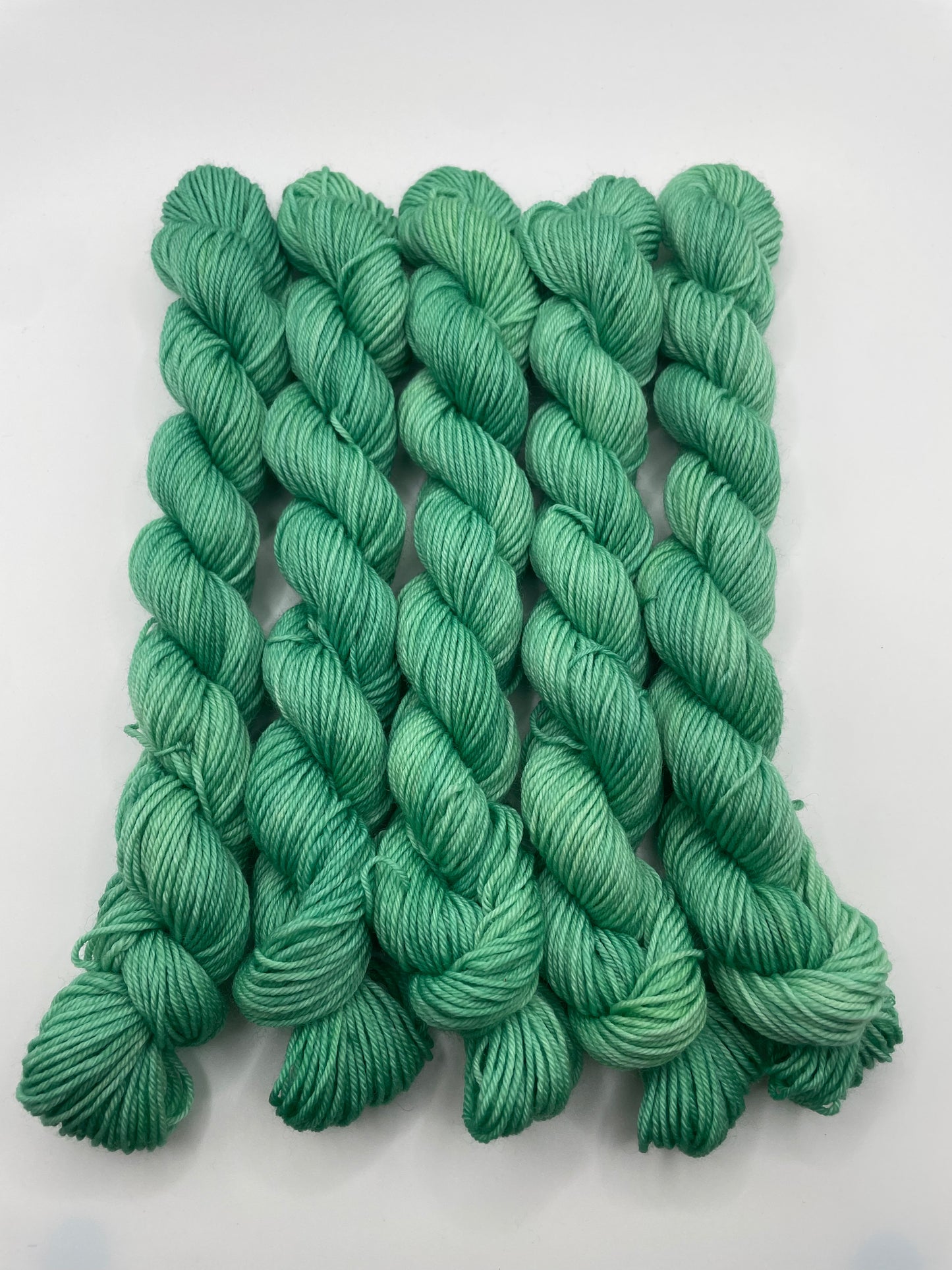 Green yarn mini skeins on a white background