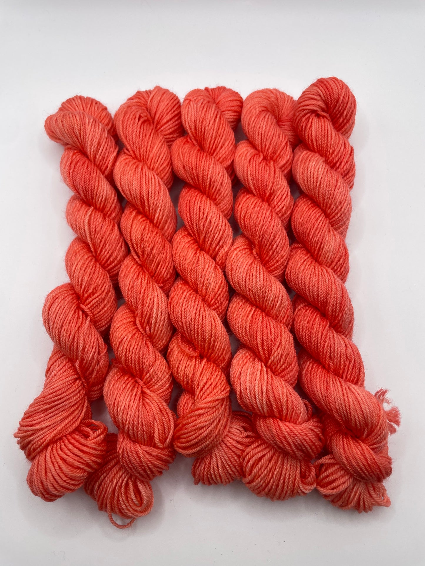 Orange red yarn mini skeins on a white background