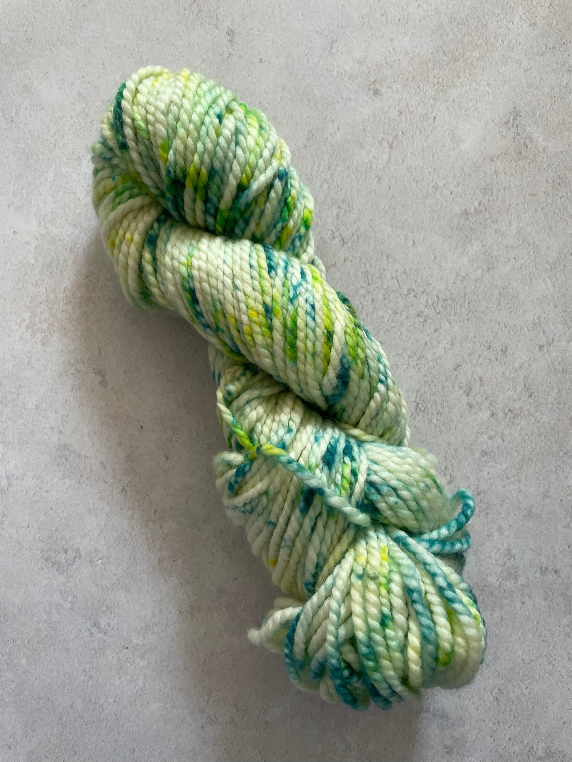 Chunky yarn skein speckled with shades of green