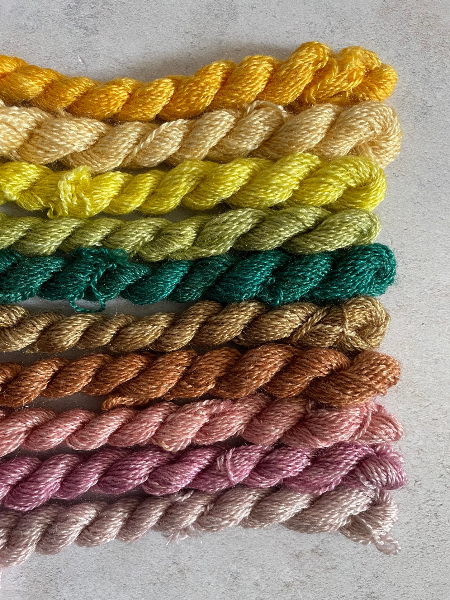 Bundle of embroidery threads in yellows greens browns and pinky purples