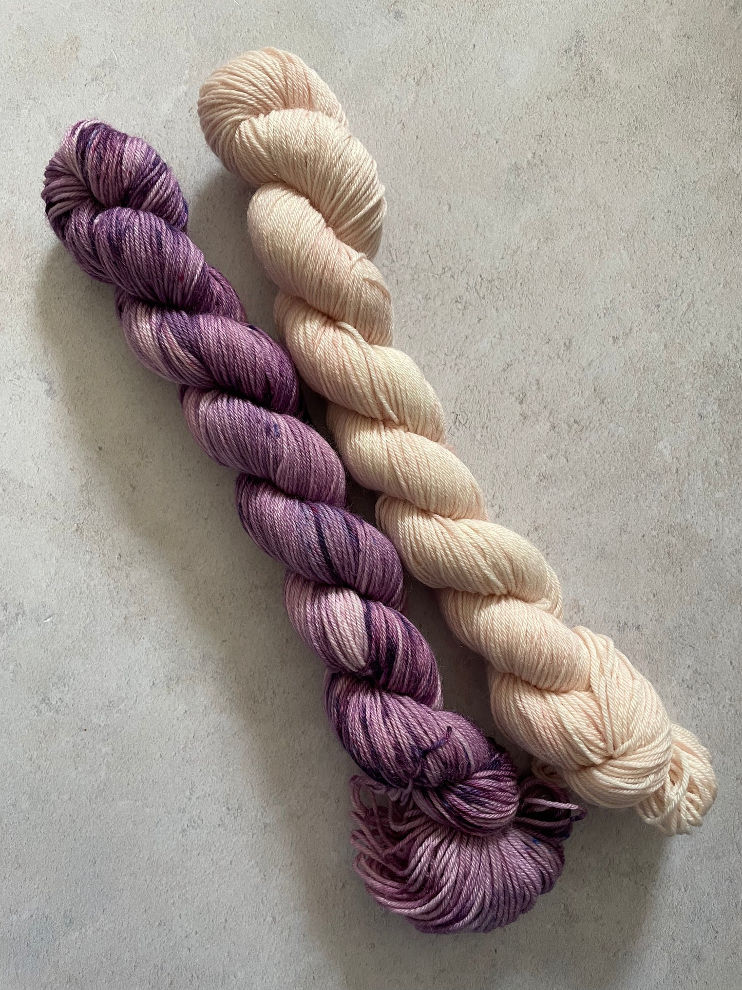 One 50g variegated purple skein and one 50g pale pink skein