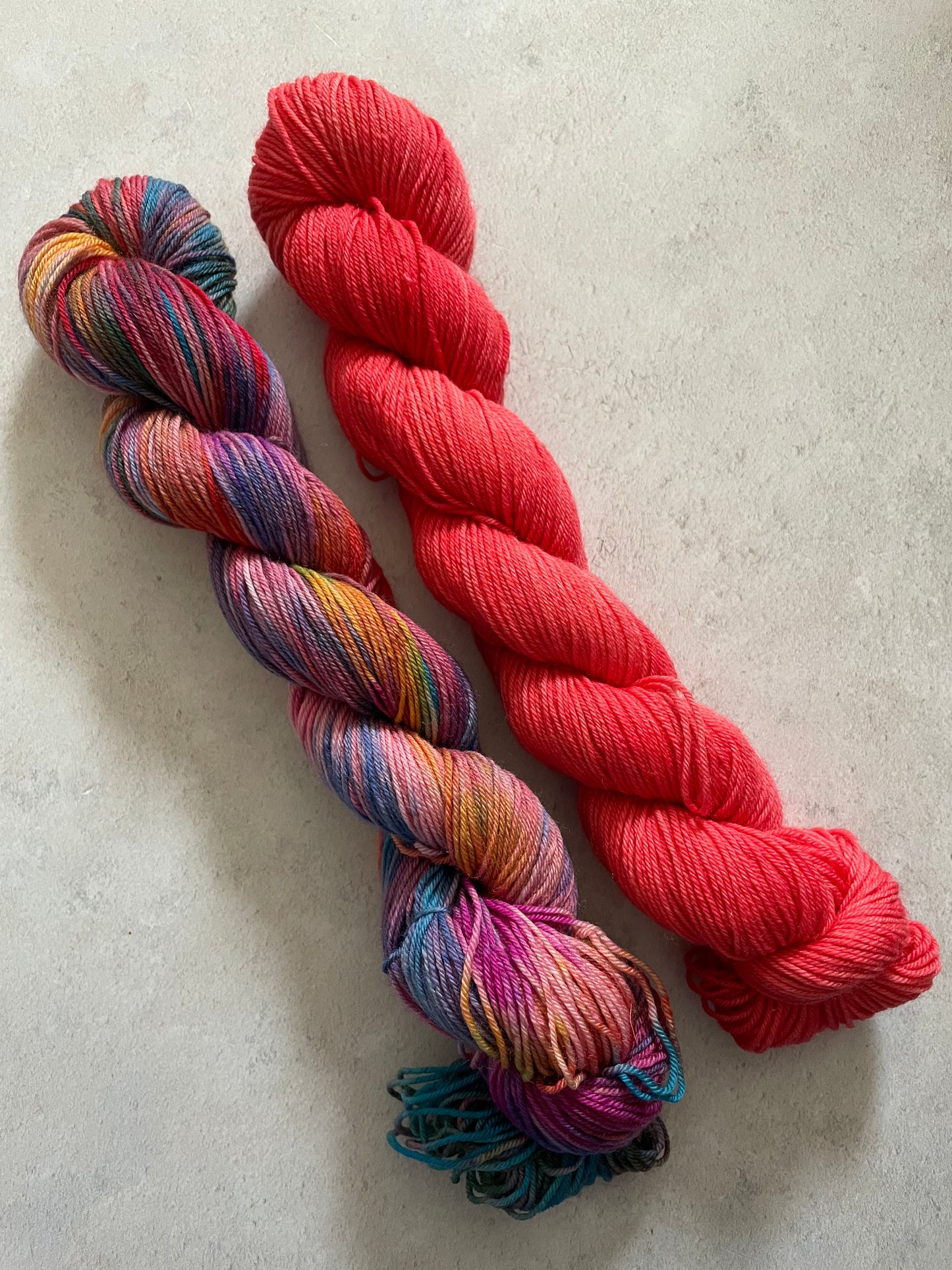 One 50g variegated red and multicoloured skein and one 50g red skein