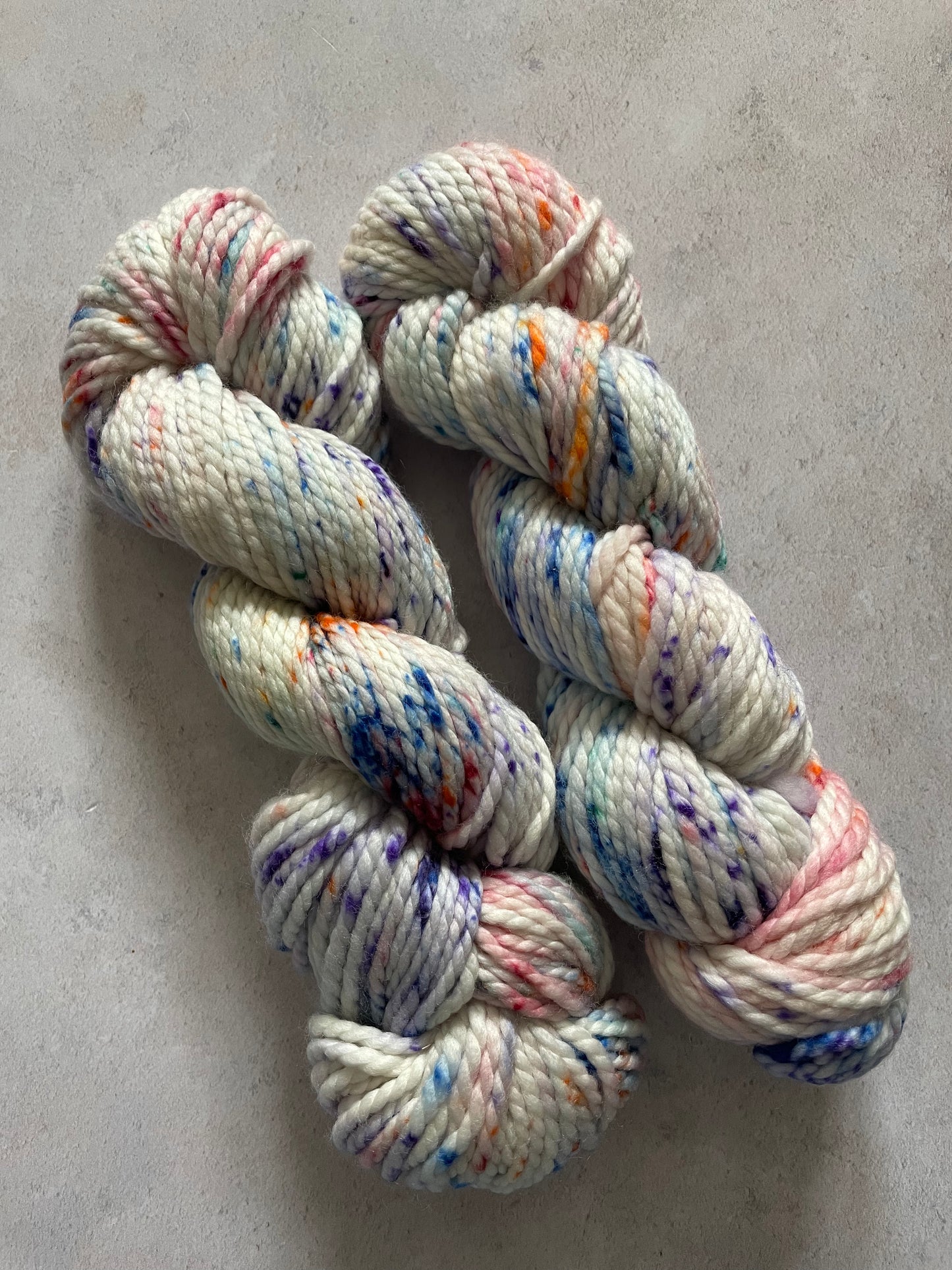 Chunky white skeins speckled with blue violet orange and red