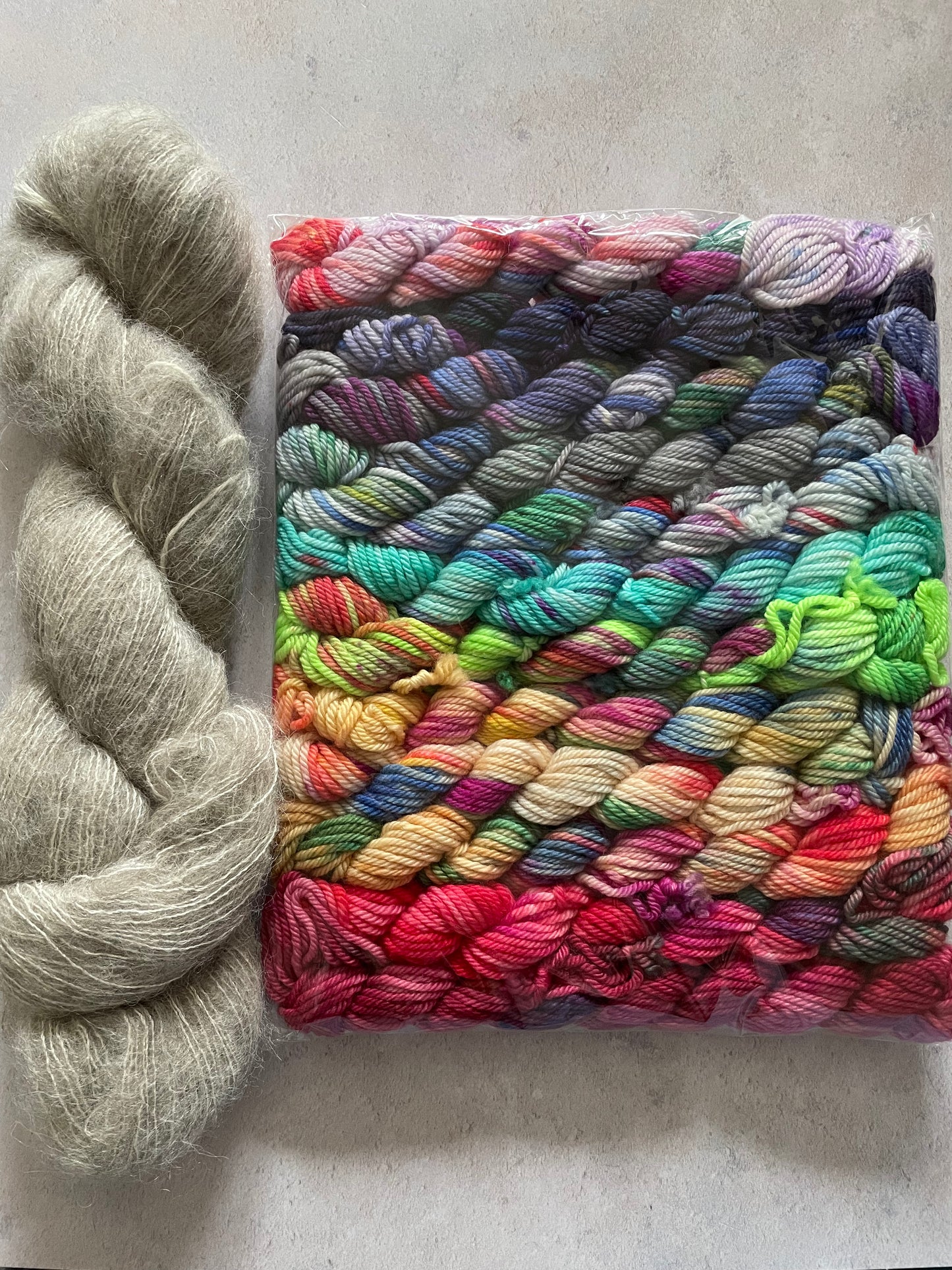 Skein of grey fluff yarn and 12 10g double knitting weight minis