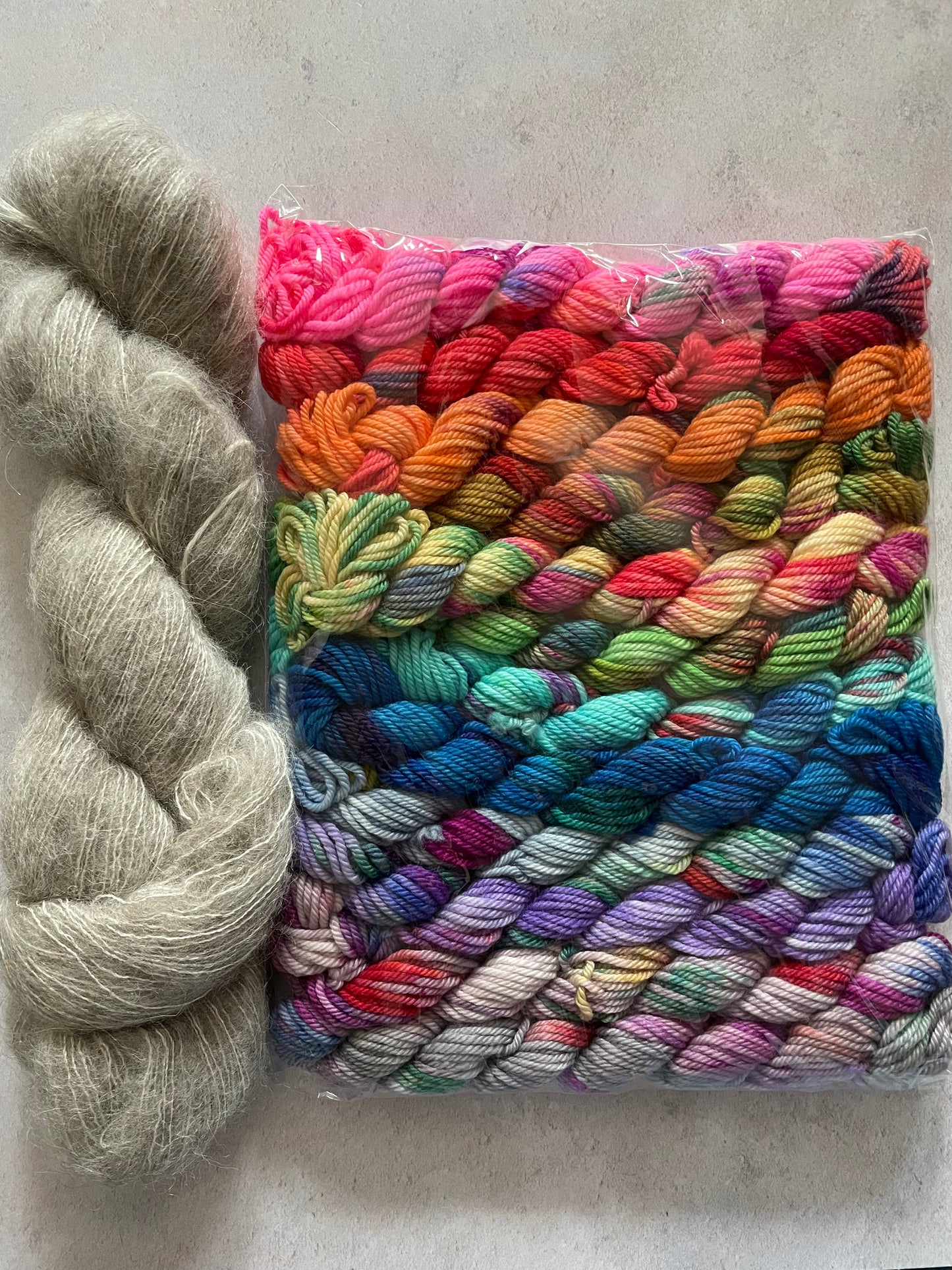 Skein of grey fluff yarn and 12 10g double knitting weight minis