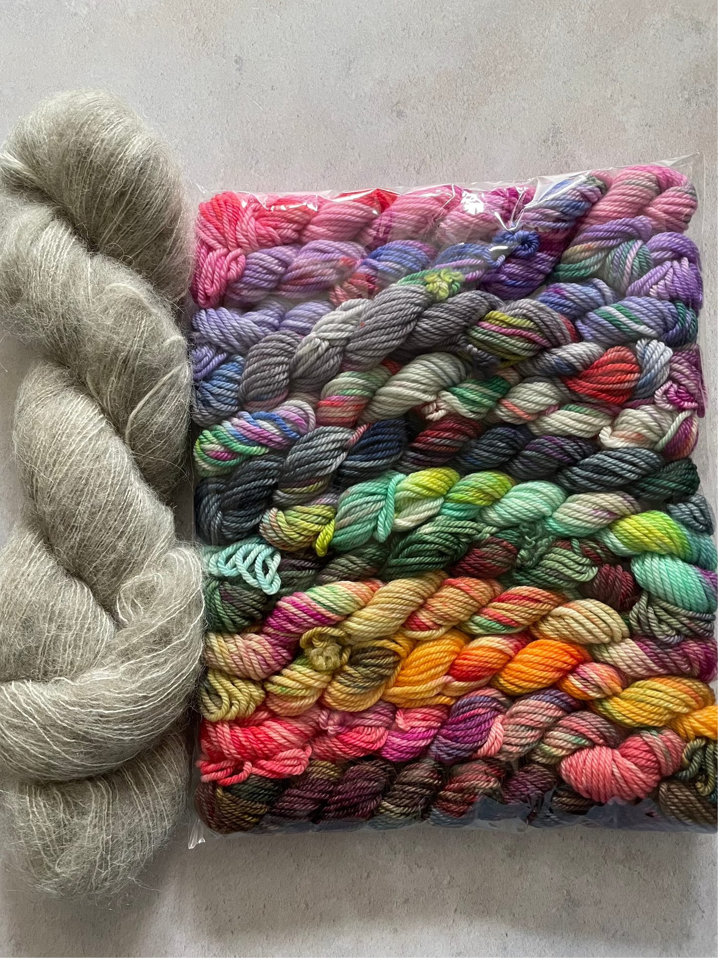 Skein of grey fluff yarn and 12 10g double knitting weight minis