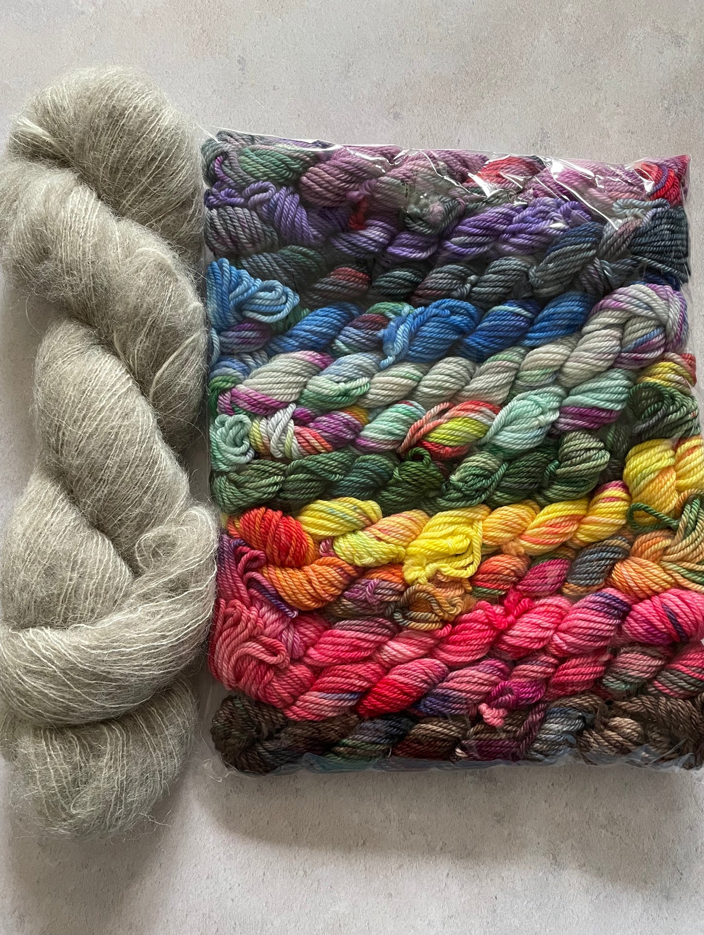 Skein of grey fluff yarn and 12 10g double knitting weight minis