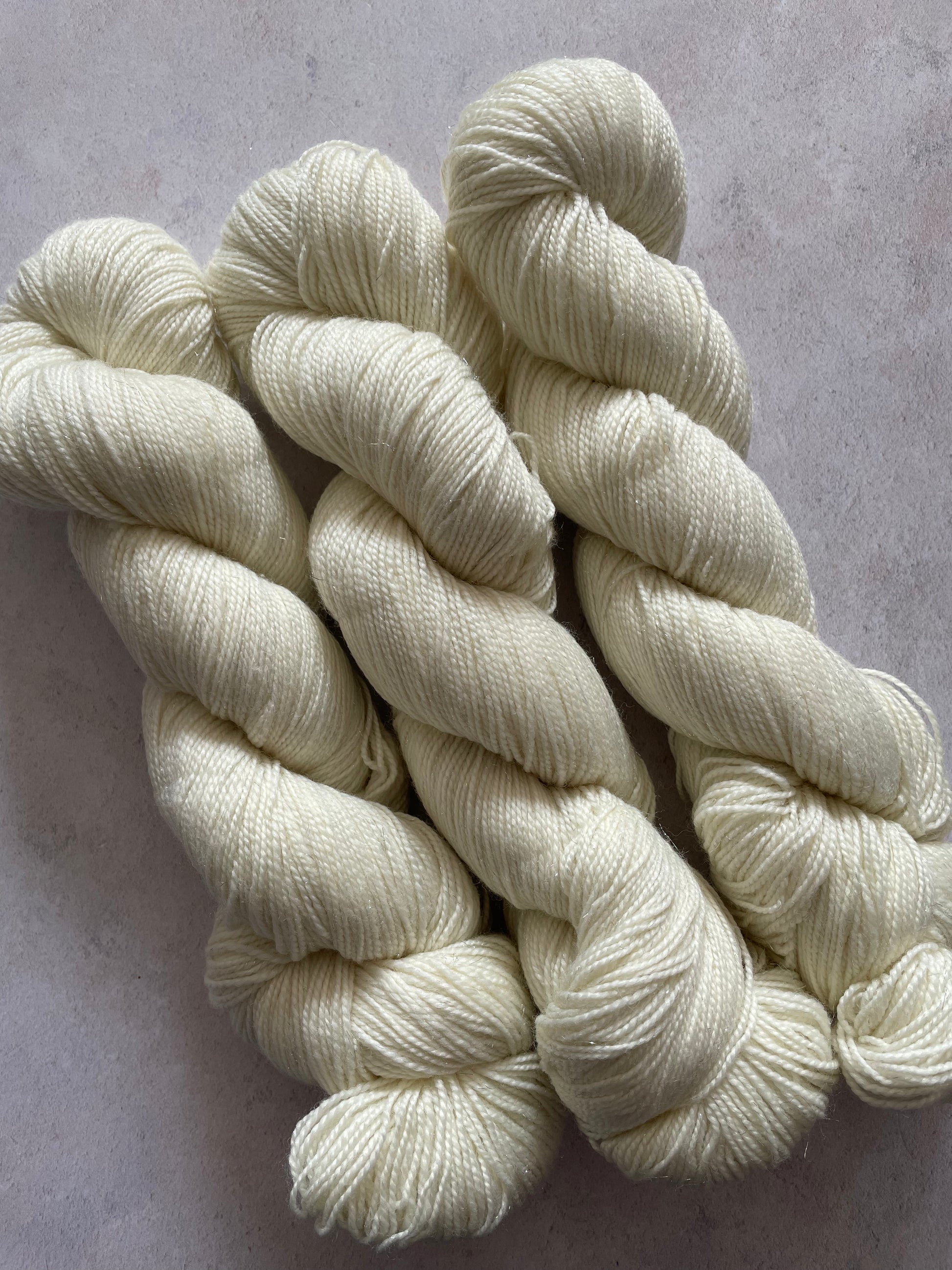 Three skeins of undyed silver sparkle sock