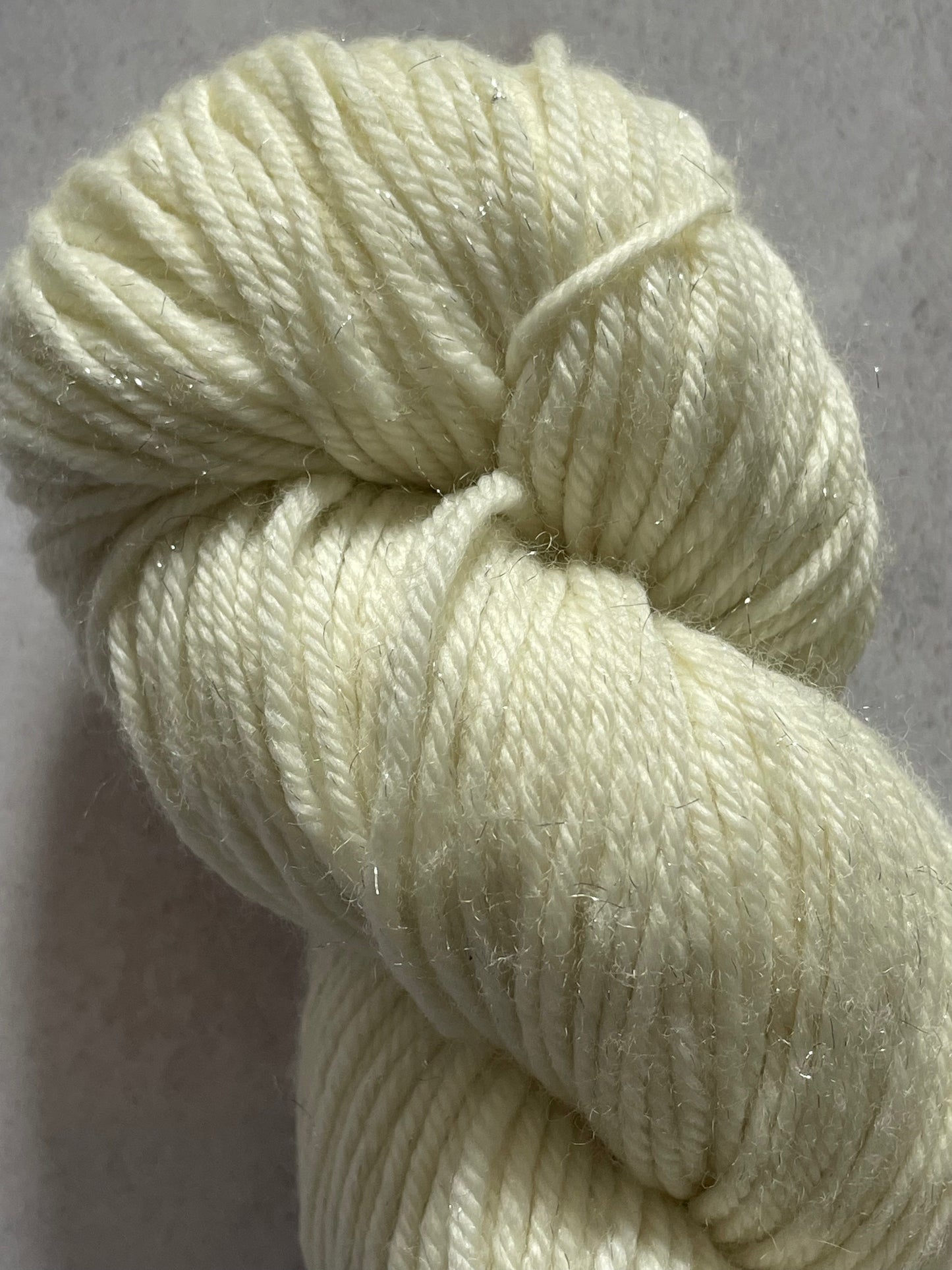 A close up of undyed silver sparkle double knitting yarn