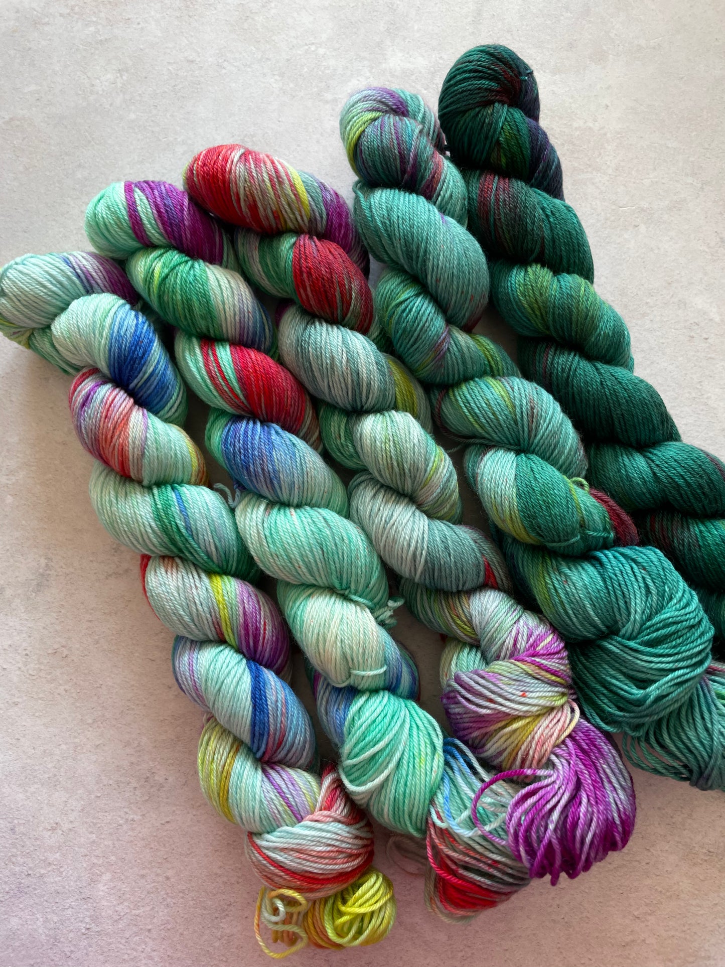 5 skeins of multicoloured and teal yarn in different shades
