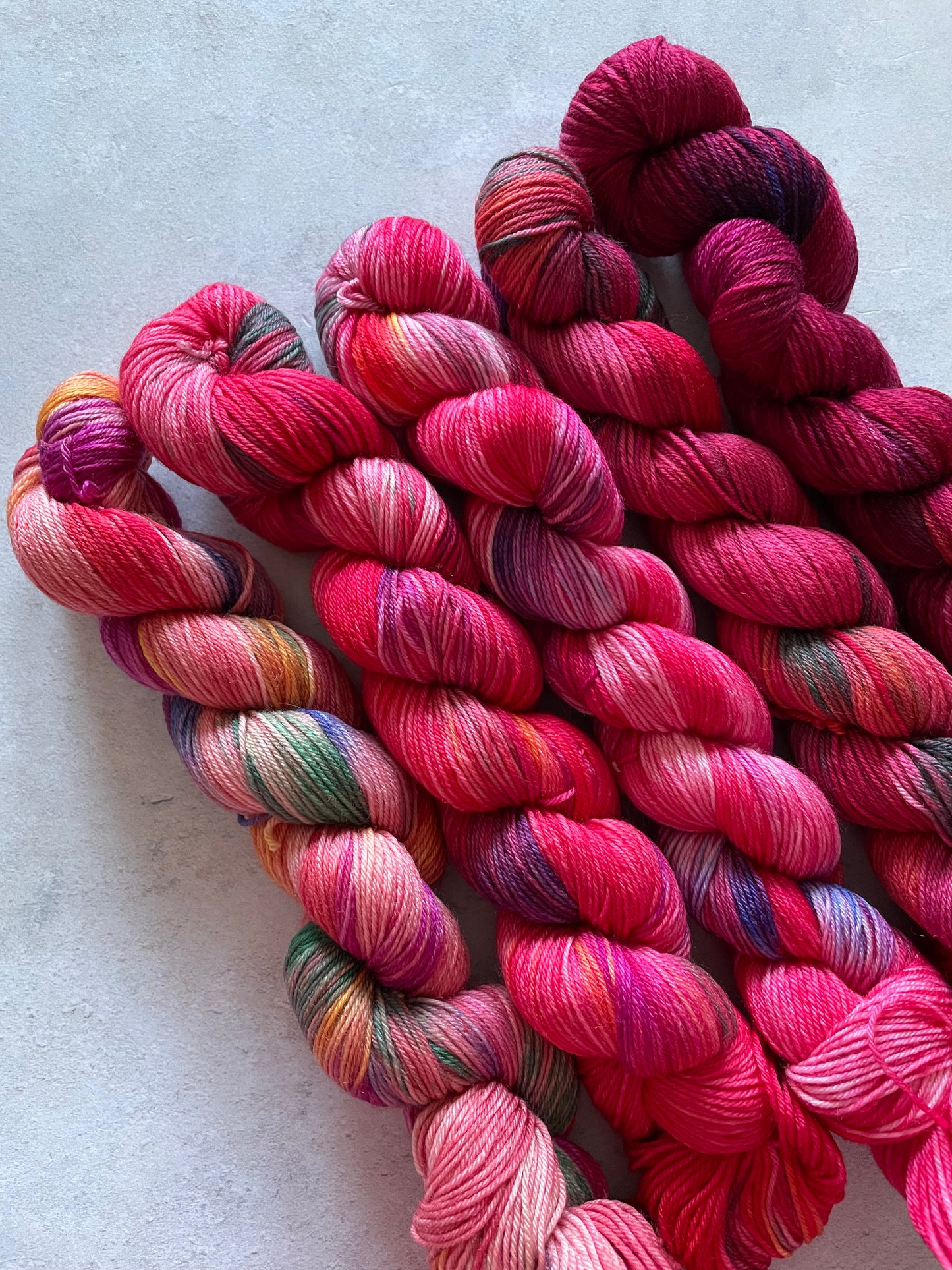 5 skeins of multicoloured and red yarn in different shades