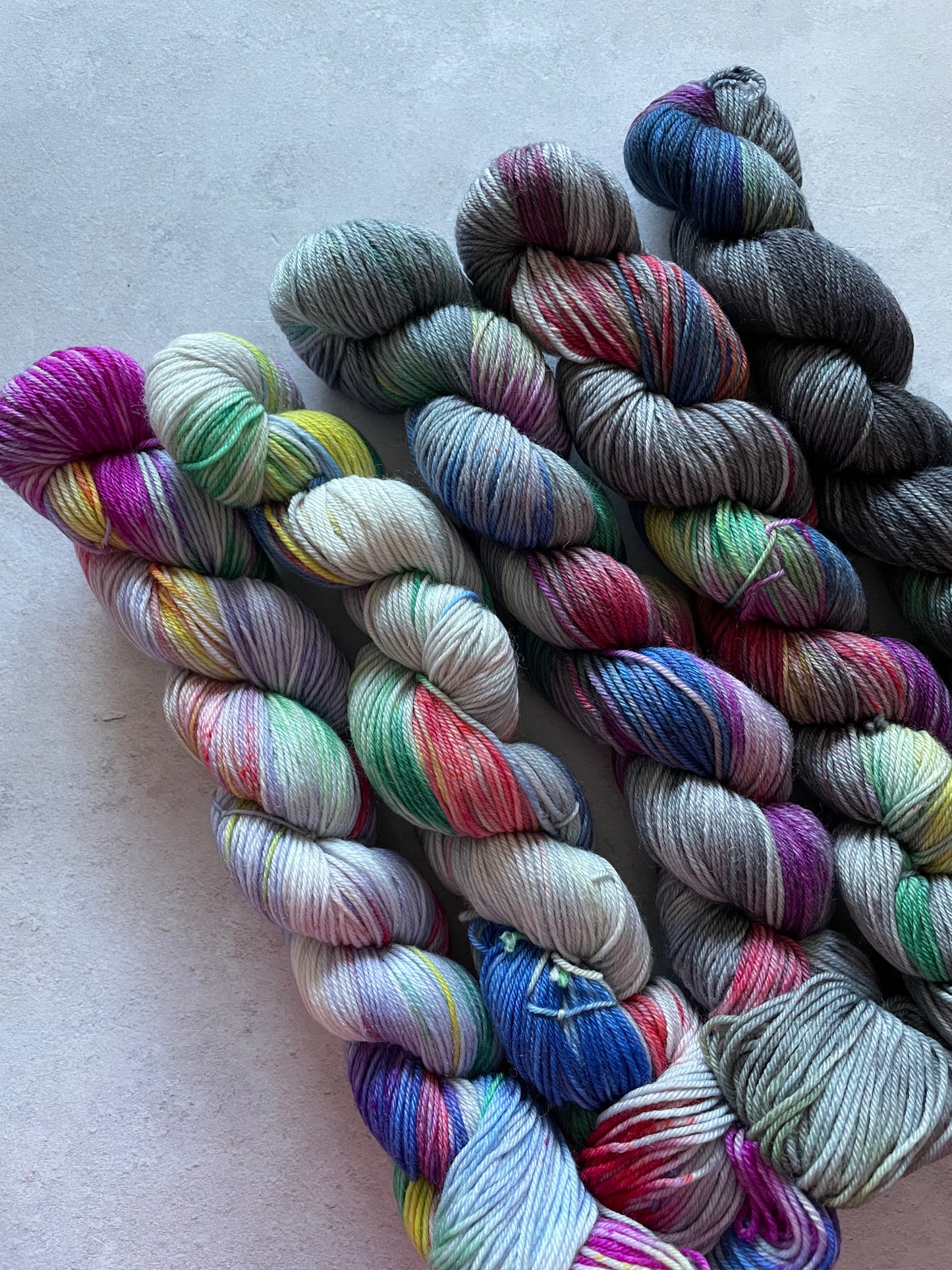 5 skeins of multicoloured and grey yarn in different shades