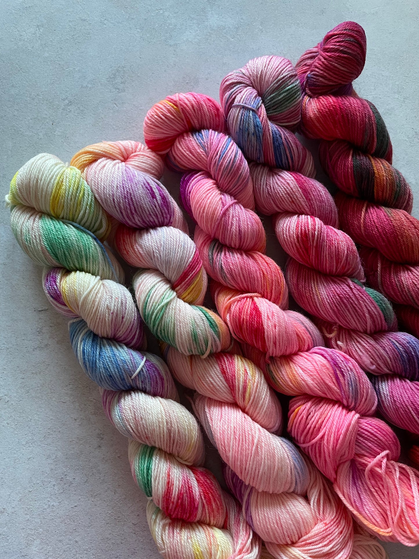 5 skeins of multicoloured and pink yarn in different shades