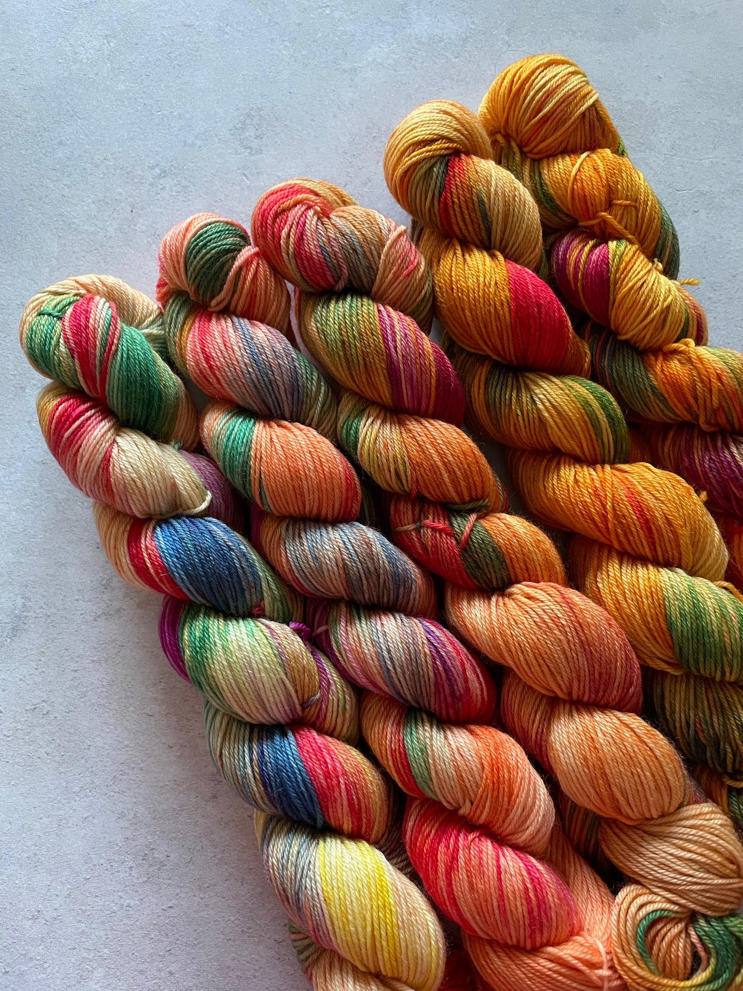 5 skeins of multicoloured and orange yarn in different shades