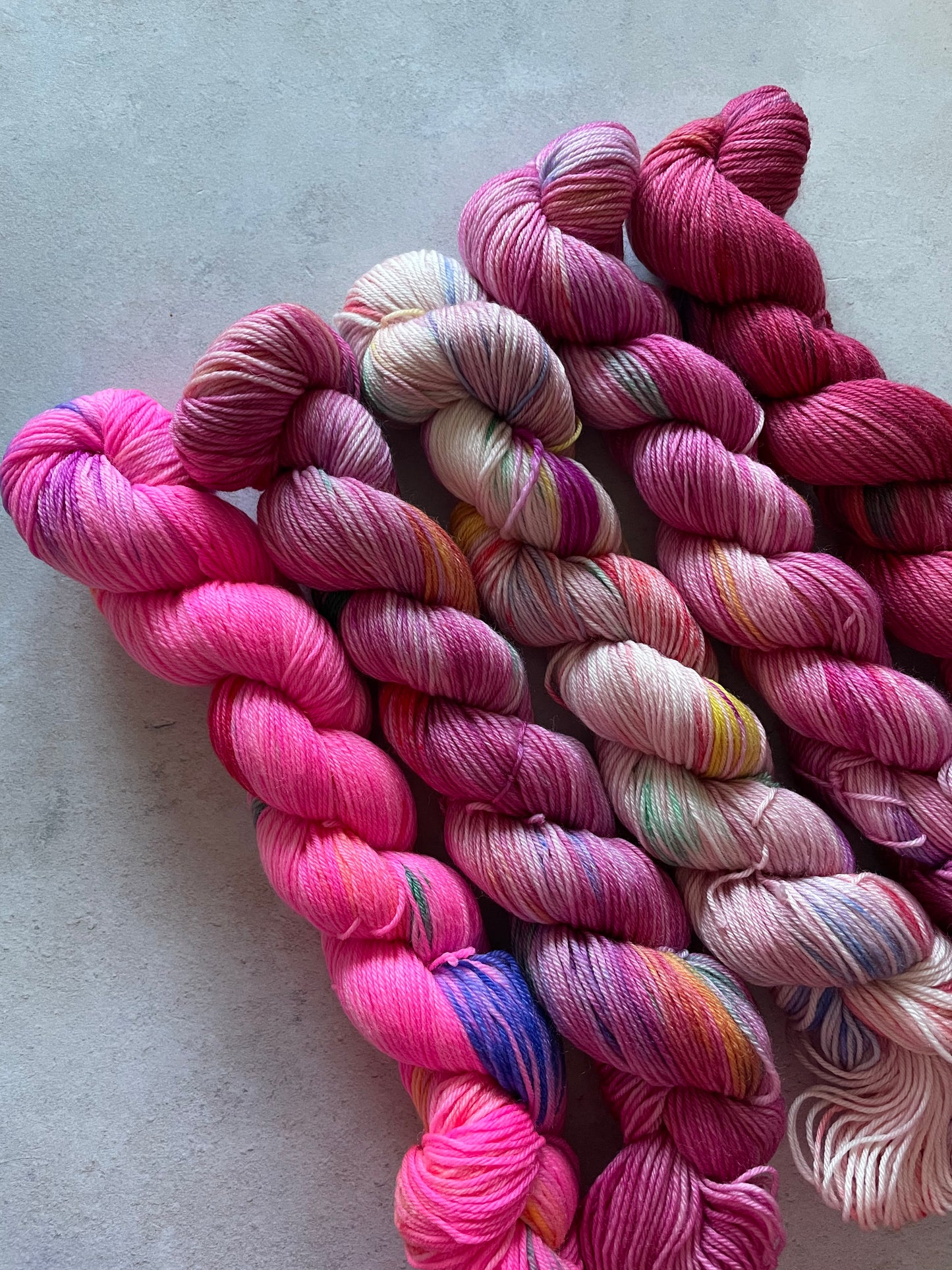 5 skeins of multicoloured and pink yarn in different shades