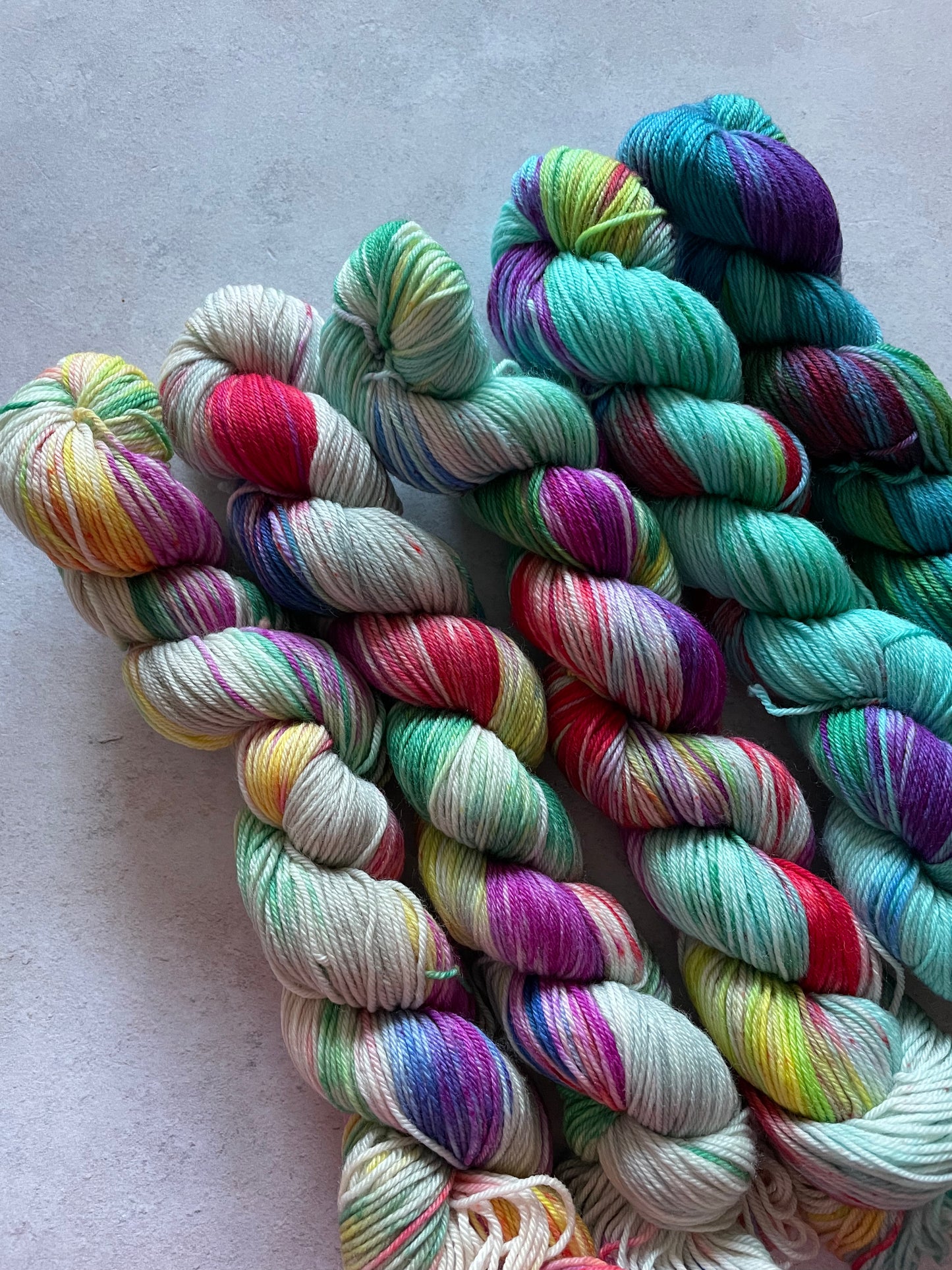 5 skeins of multicoloured and turquoise blue yarn in different shades