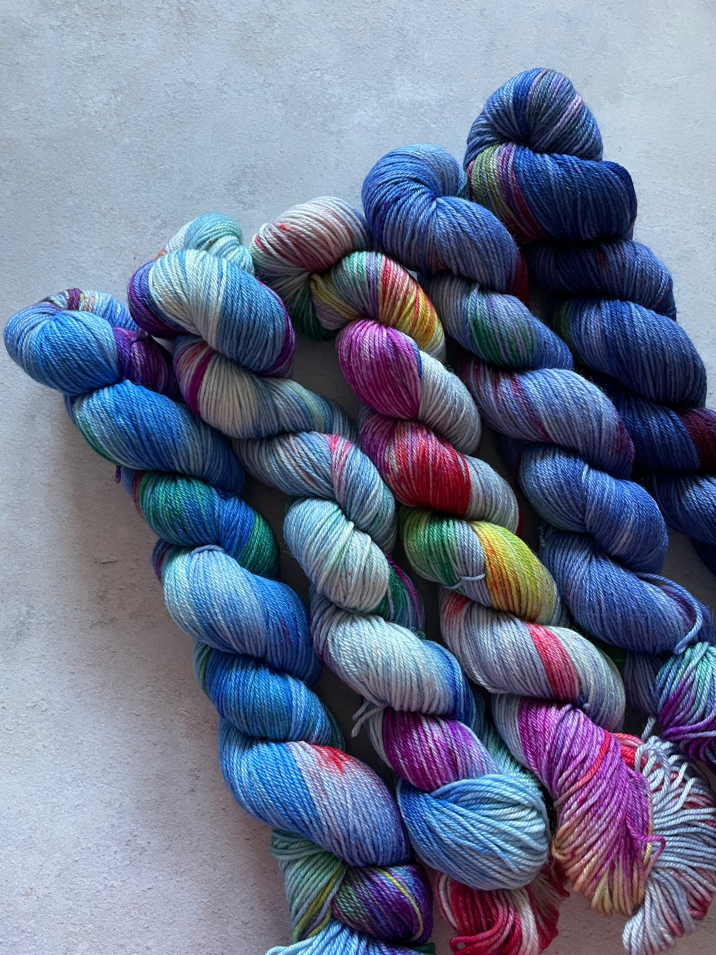 5 skeins of multicoloured and blue yarn in different shades
