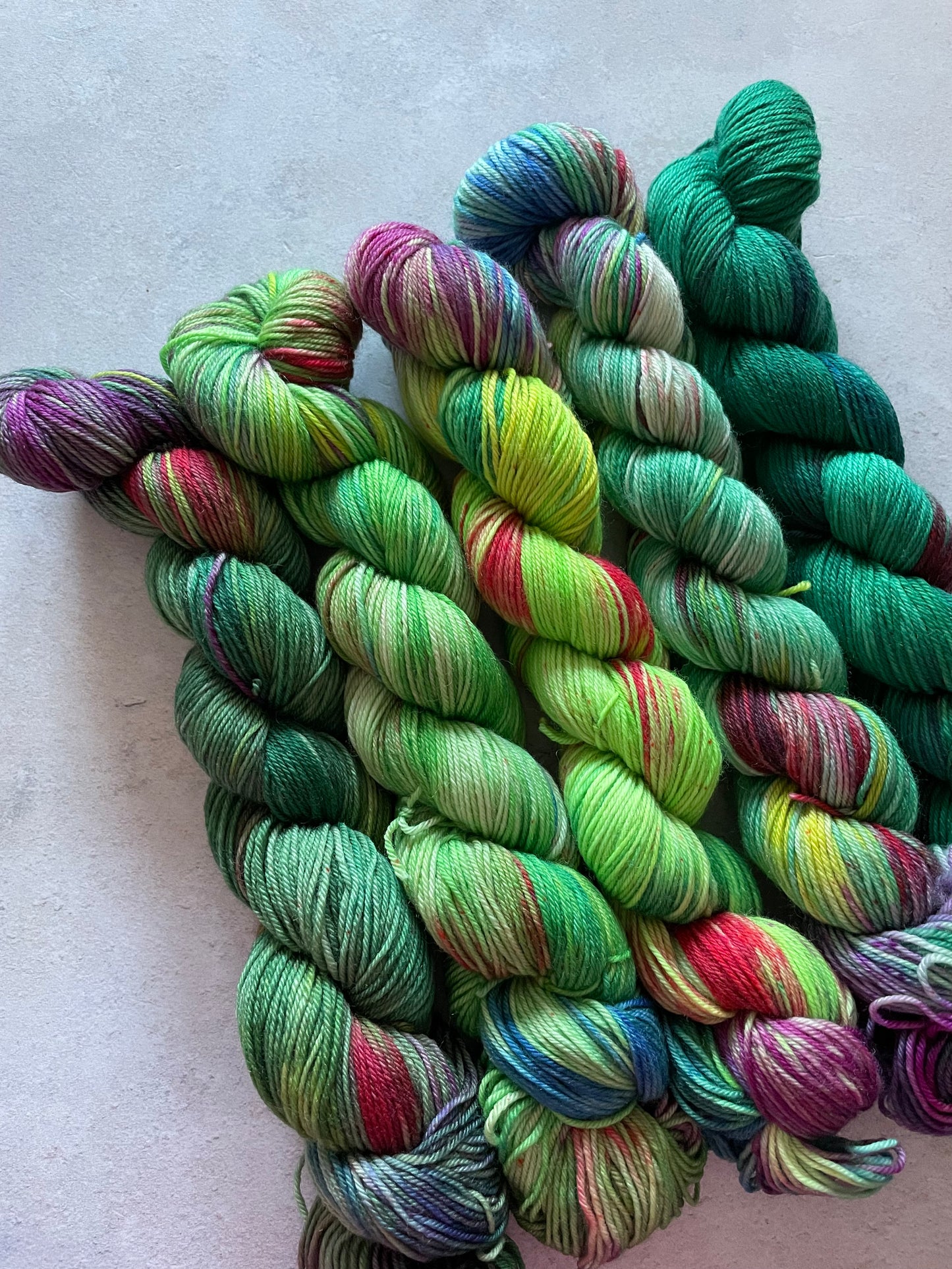 5 skeins of multicoloured and green yarn in different shades