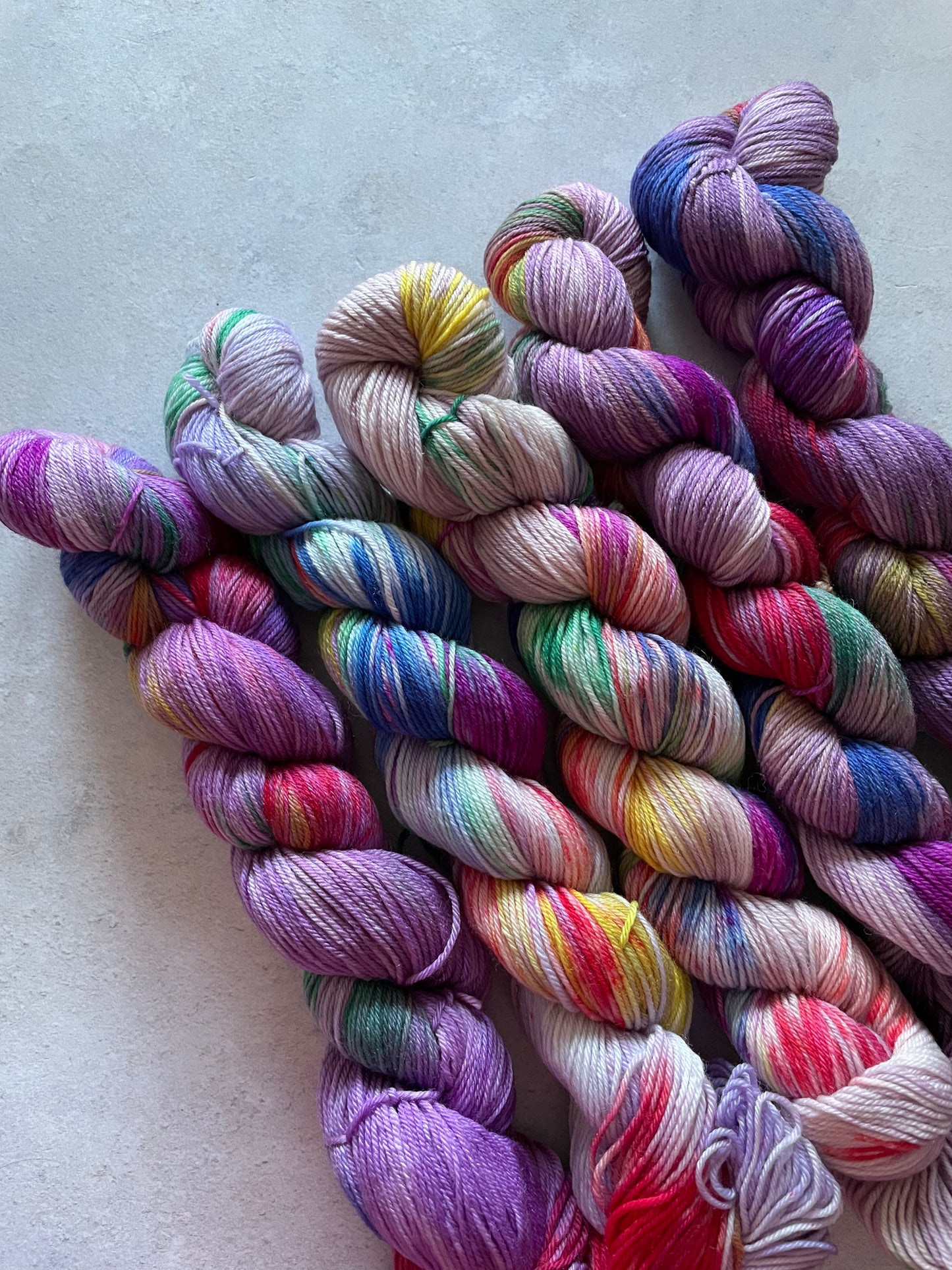 5 skeins of multicoloured and purple yarn in different shades