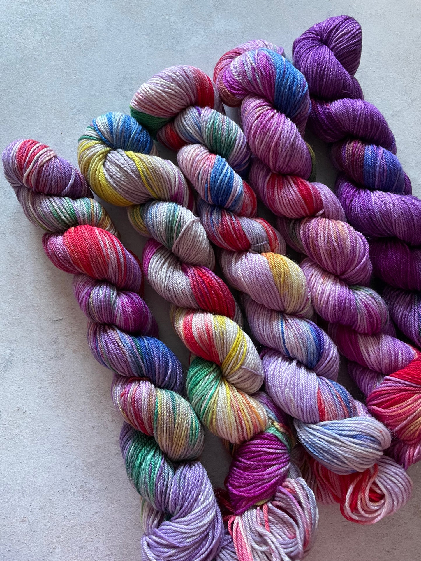 5 skeins of multicoloured and purple yarn in different shades