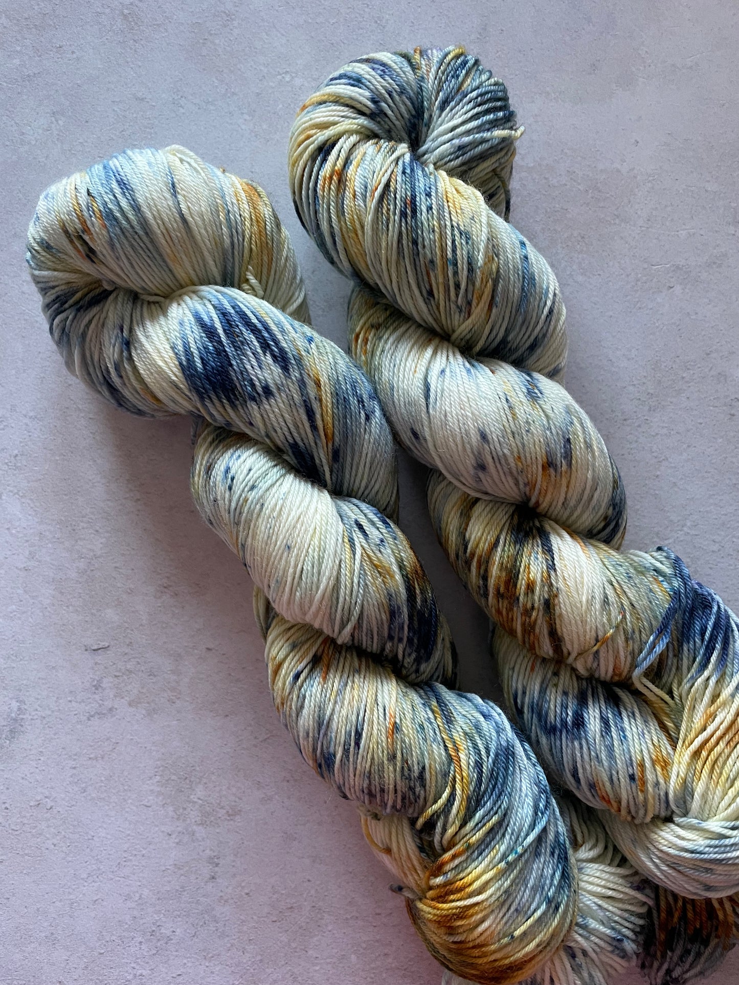 2 skeins of yarn with blue and gold speckles