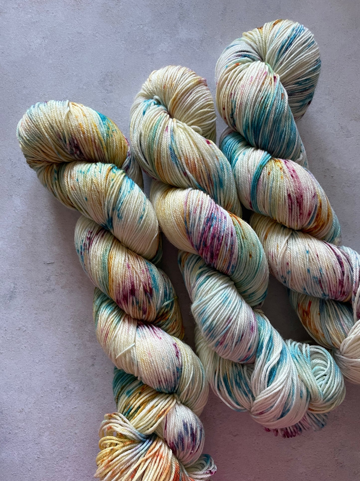 3 skeins of sock yarn with blue gold and purple speckles