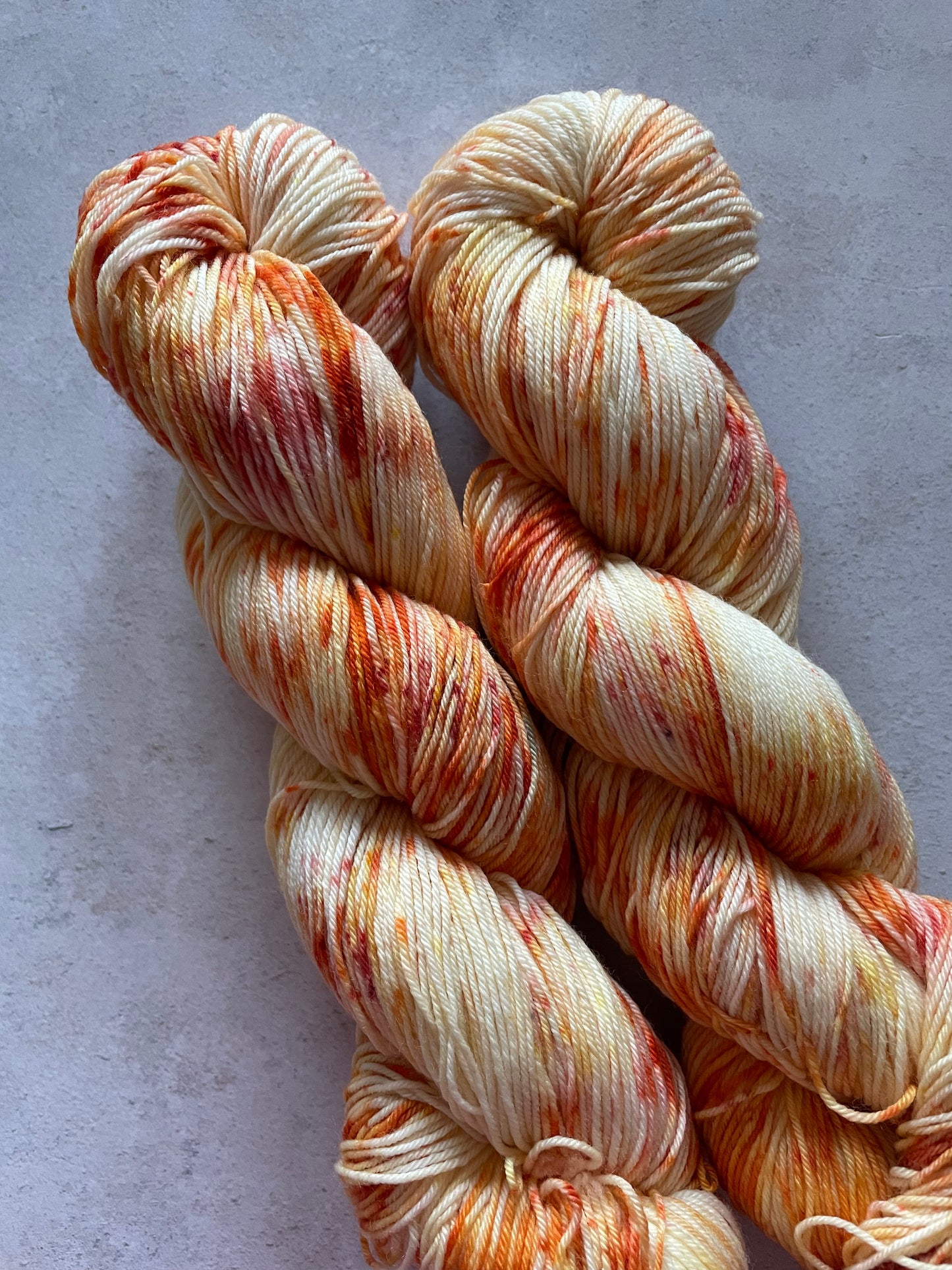 2 skeins of yarn with orange and red speckles