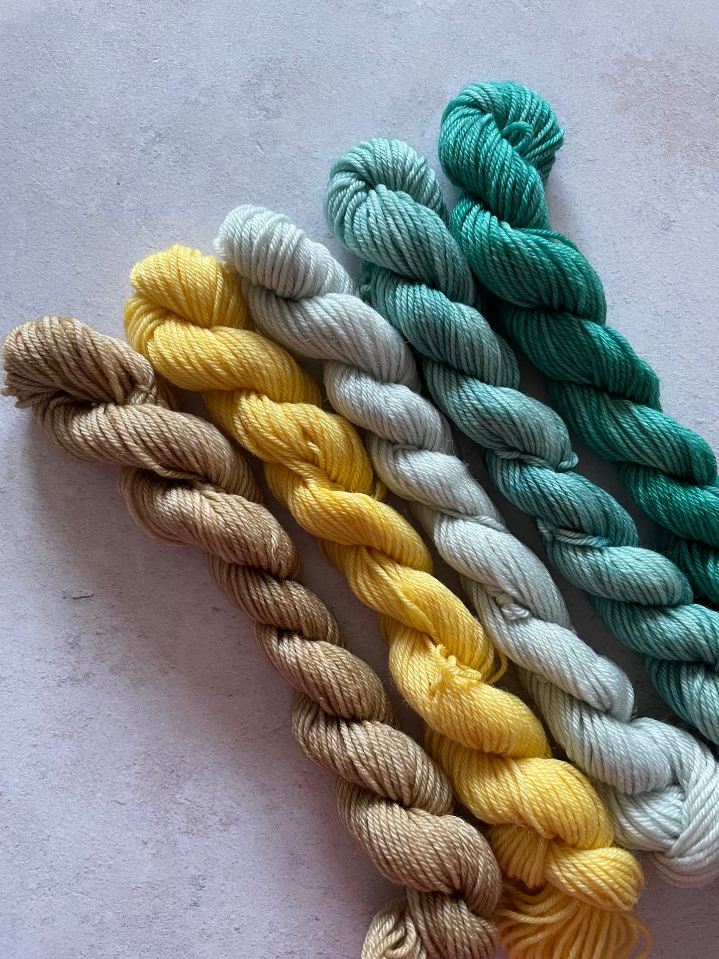 5 mini skeins in beige yellow and shades of teal