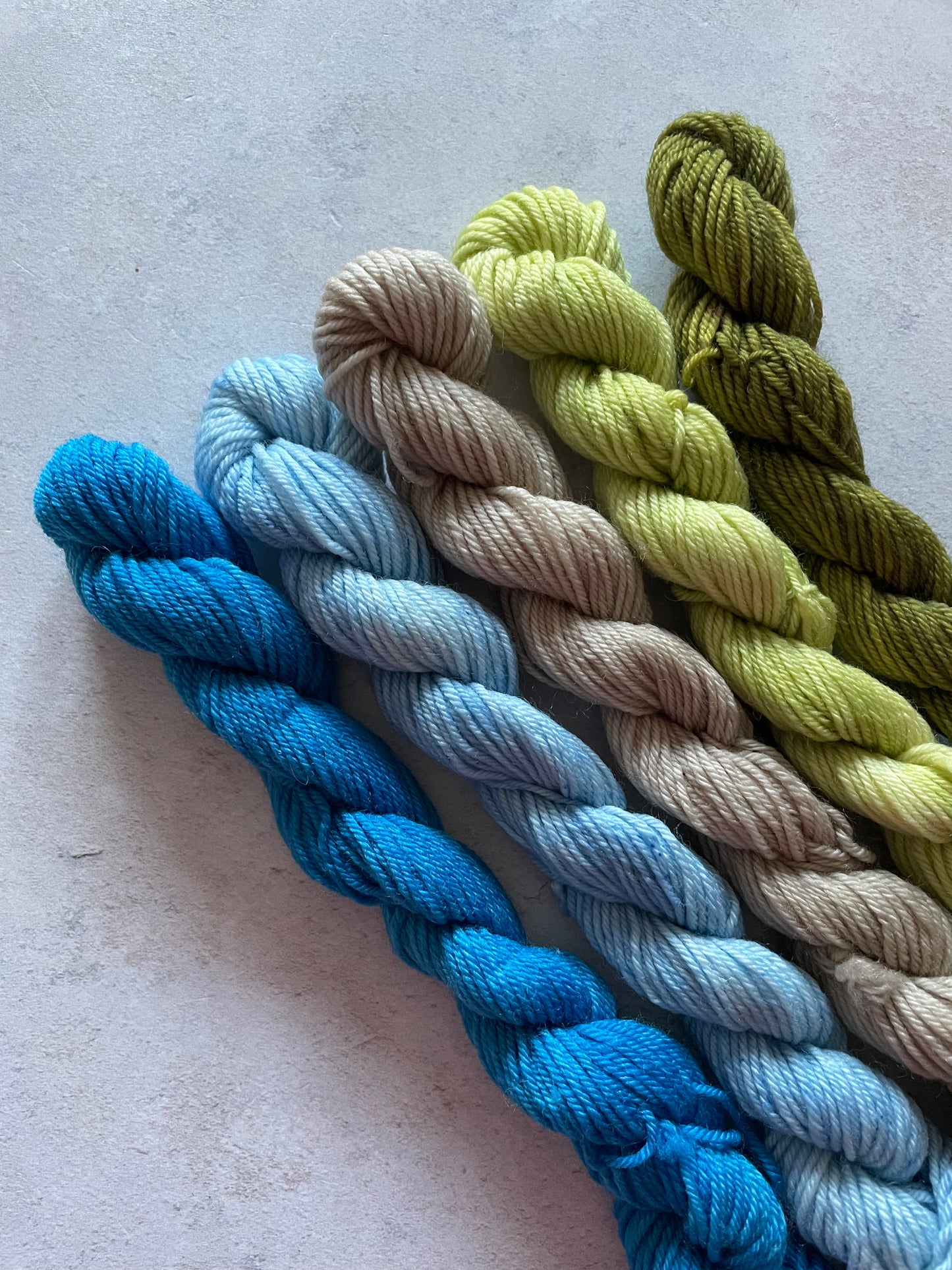 5 mini skeins in shades of blue, beige and green