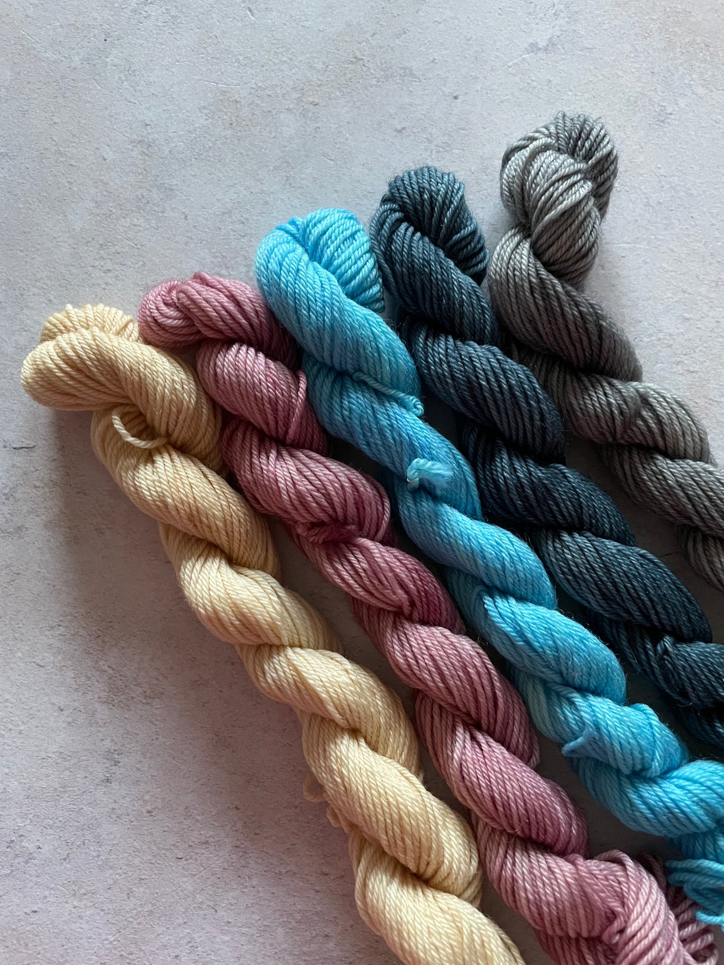 5 mini skeins in shades of beige purple blue and grey