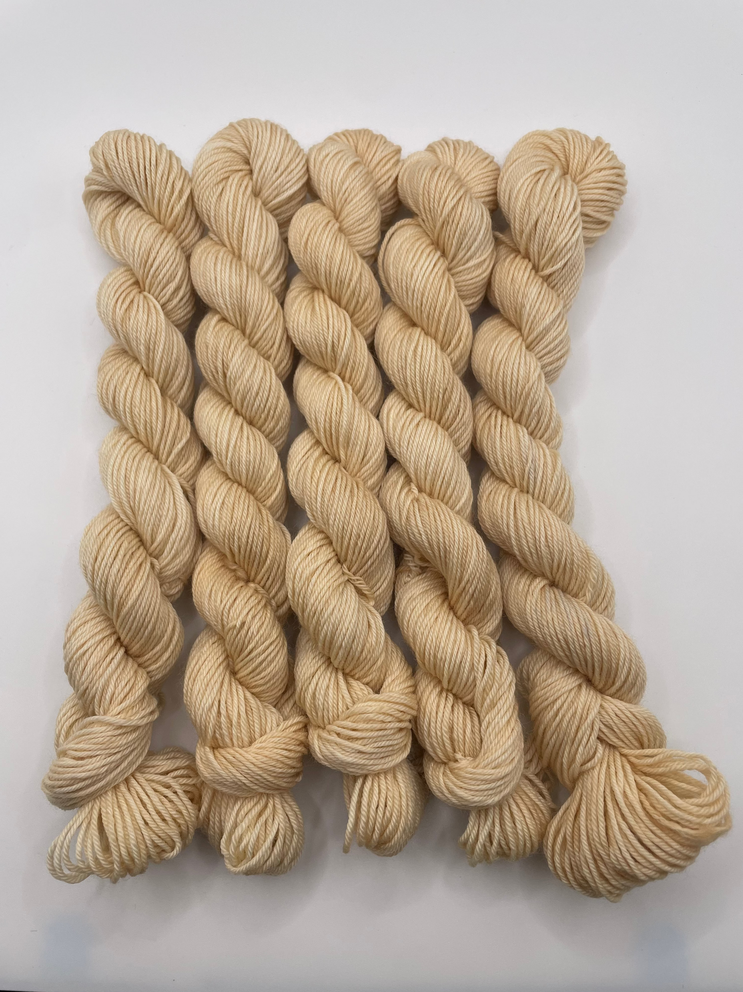 Cream yarn mini skeins on a white background