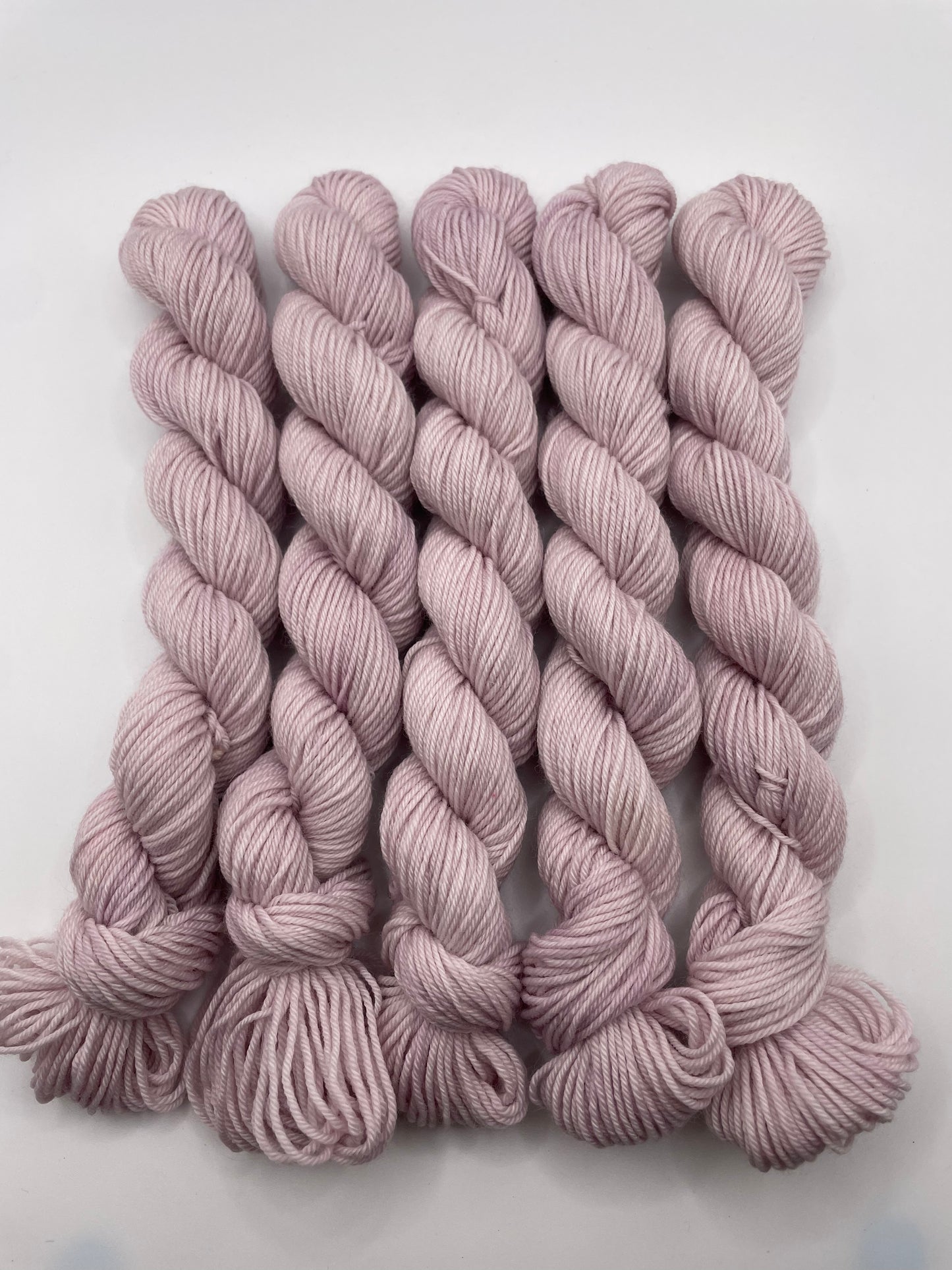 Pale purple yarn mini skeins on a white background
