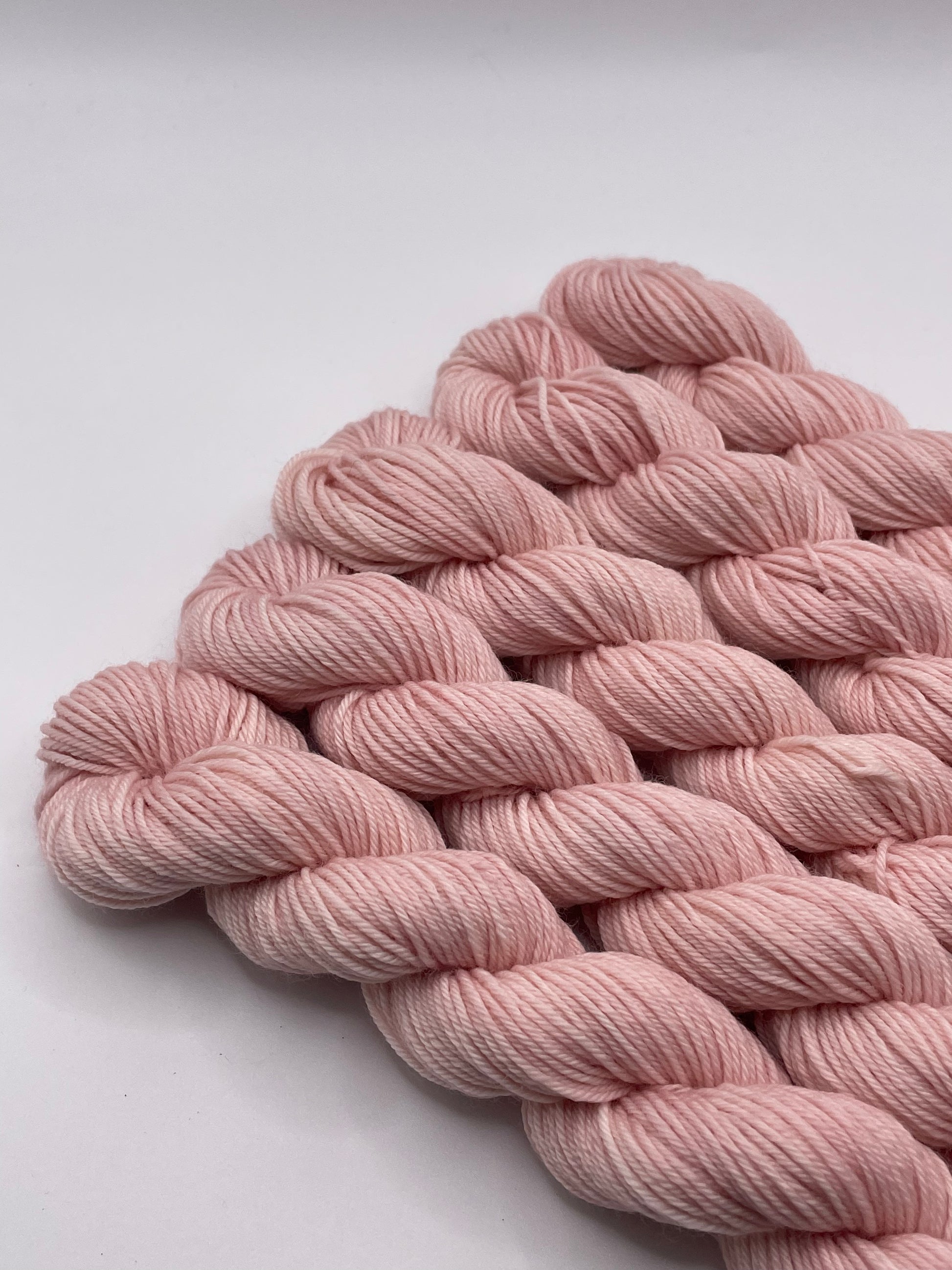 Pale pink yarn mini skeins on a white background