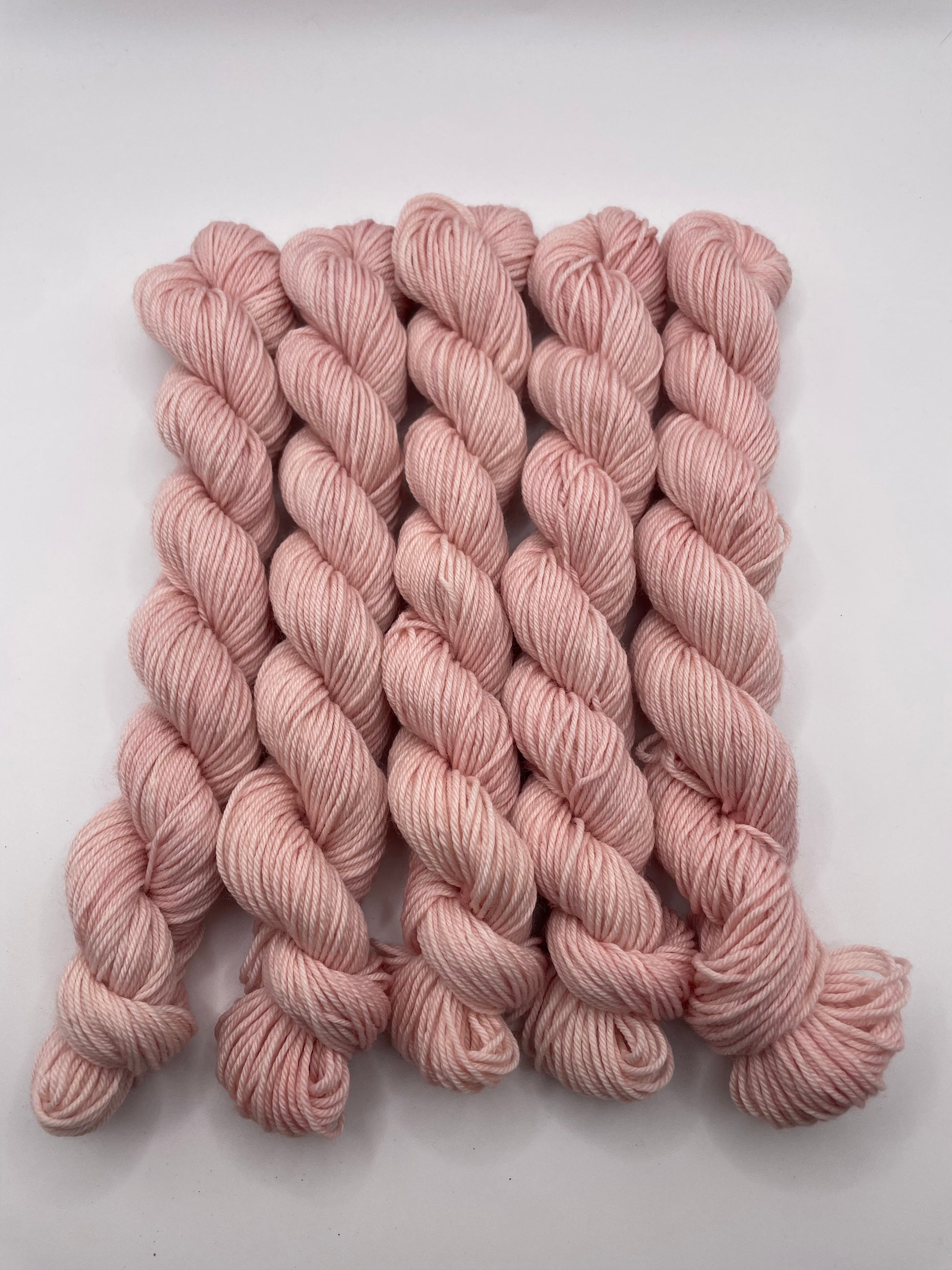 Pale pink yarn mini skeins on a white background