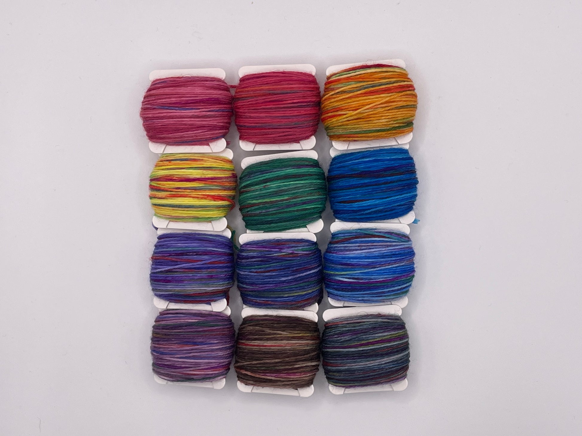 12 yarn bobbins in a rainbow of colours