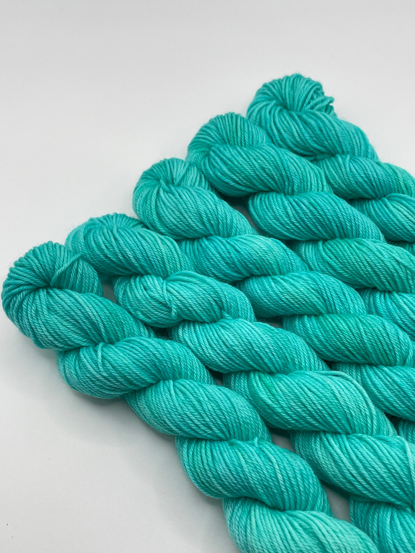 Teal yarn mini skeins on a white background