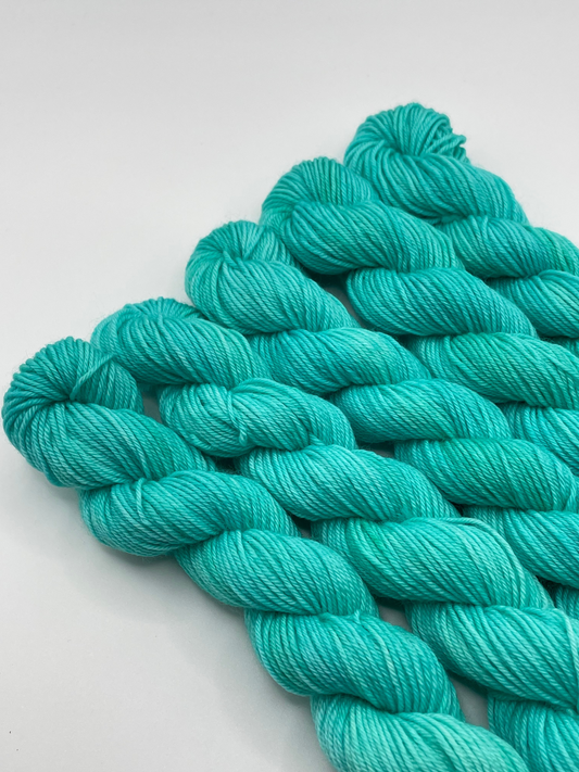Teal yarn mini skeins on a white background