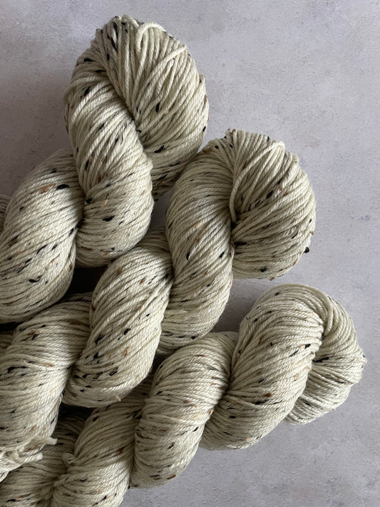 3 skeins of cream double knitting yarn with black and tan neps