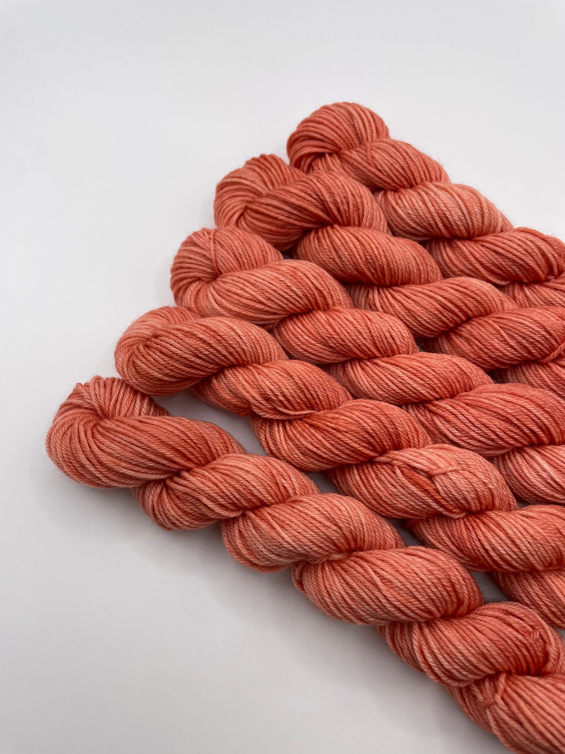 Orange red yarn mini skeins on a white background