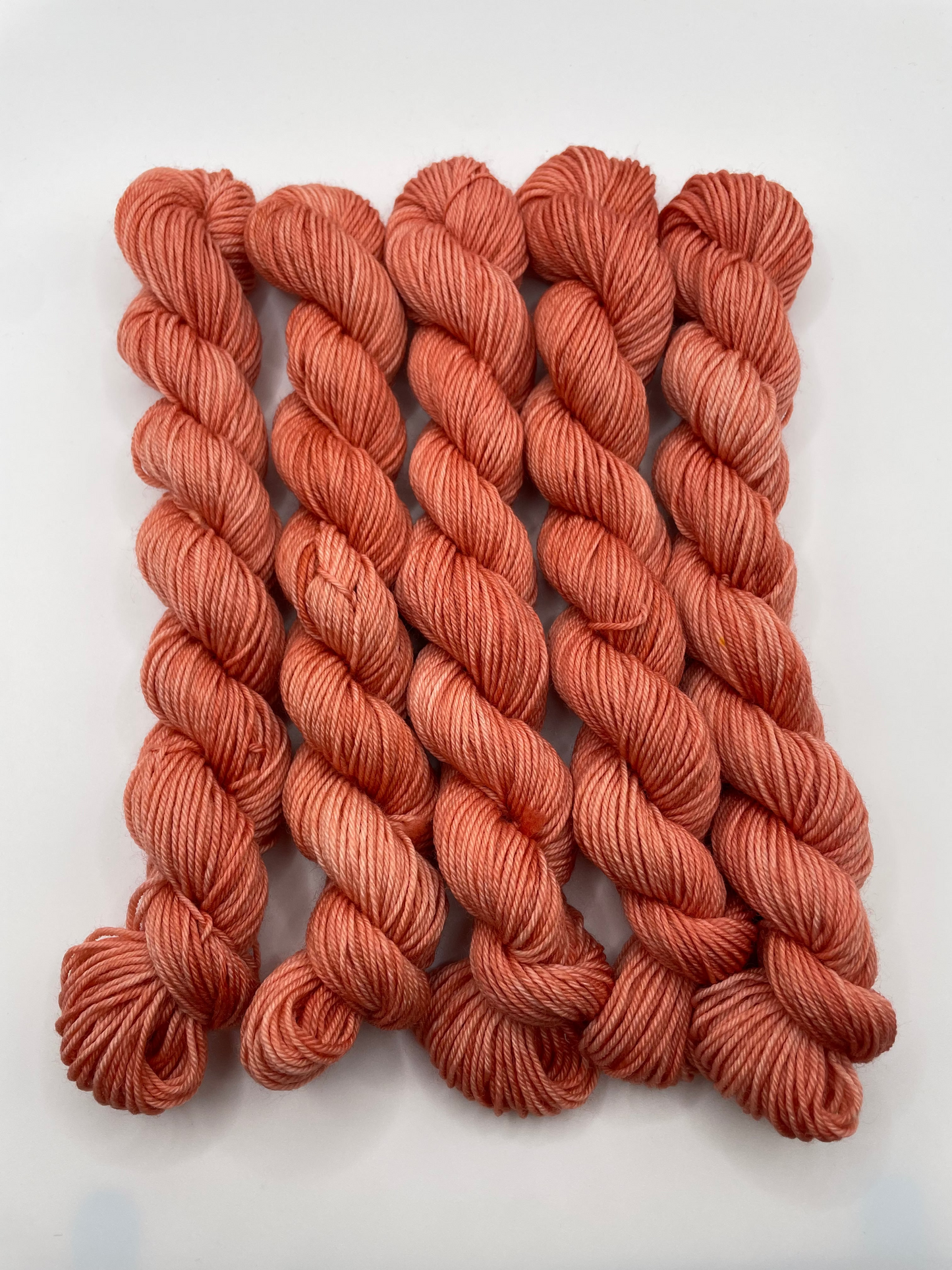 Orange red yarn mini skeins on a white background