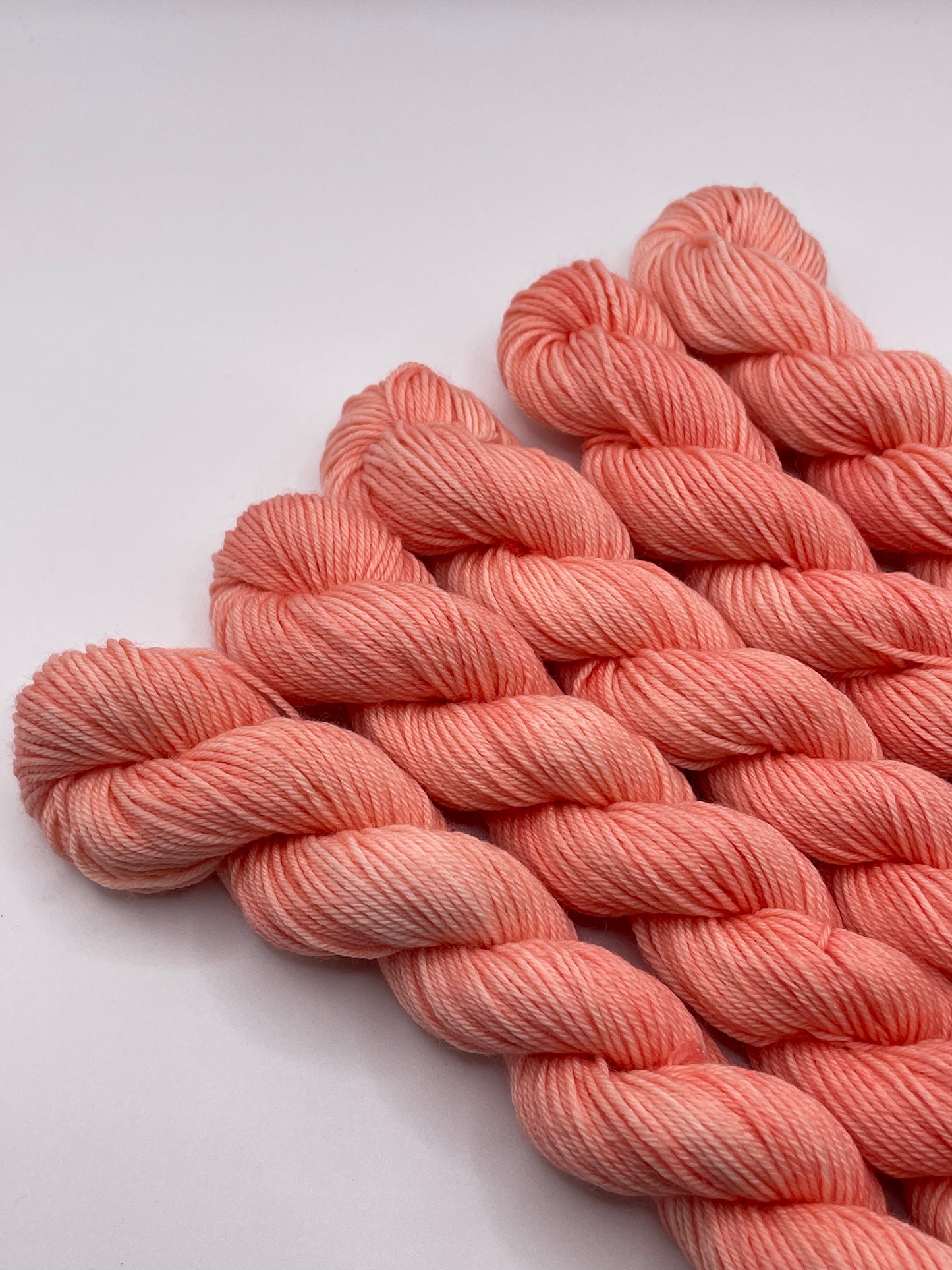 Peachy coral yarn mini skeins on a white background