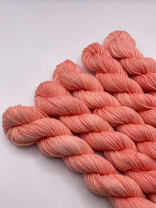 Peachy coral yarn mini skeins on a white background