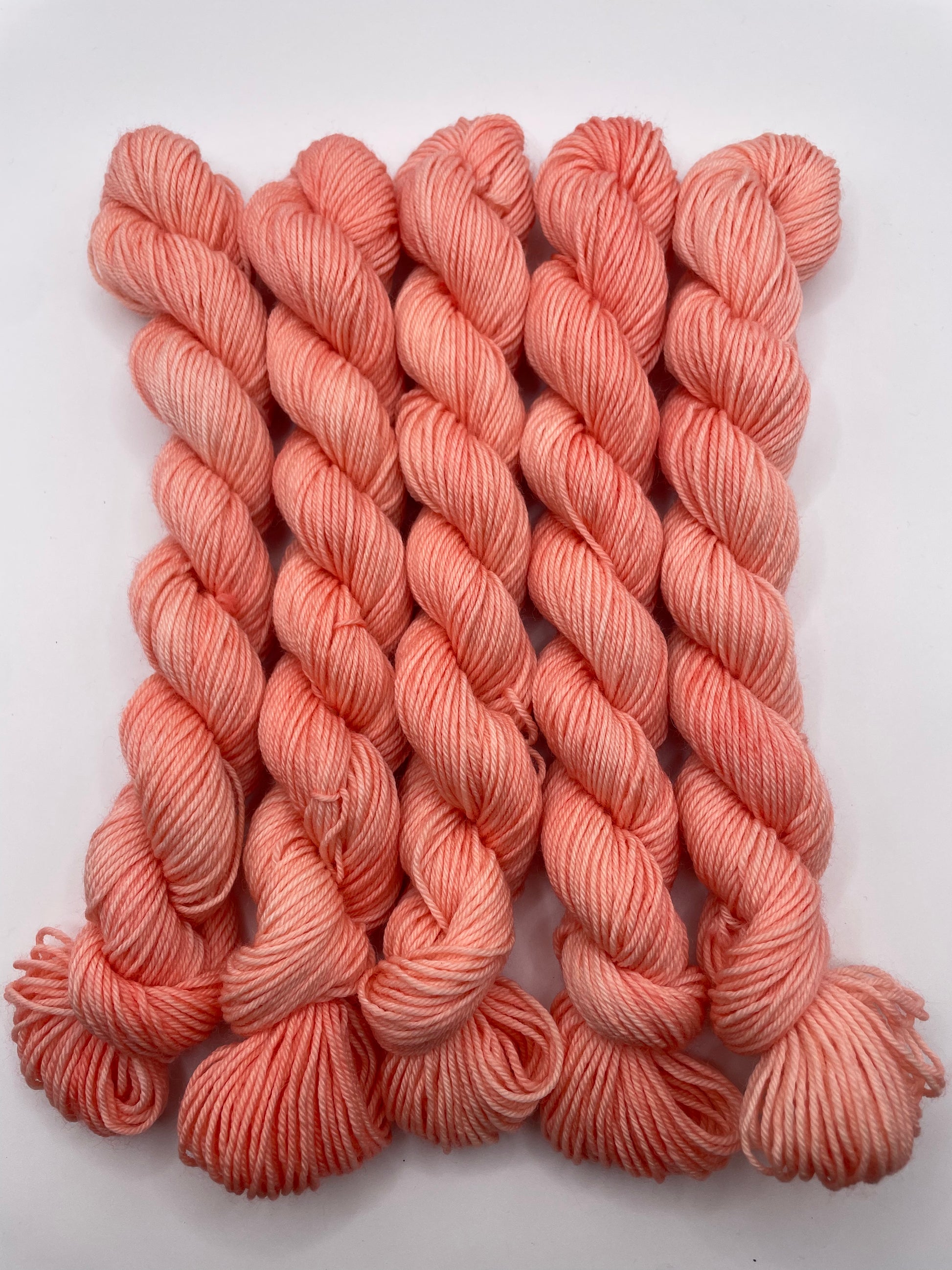 Peachy coral yarn mini skeins on a white background