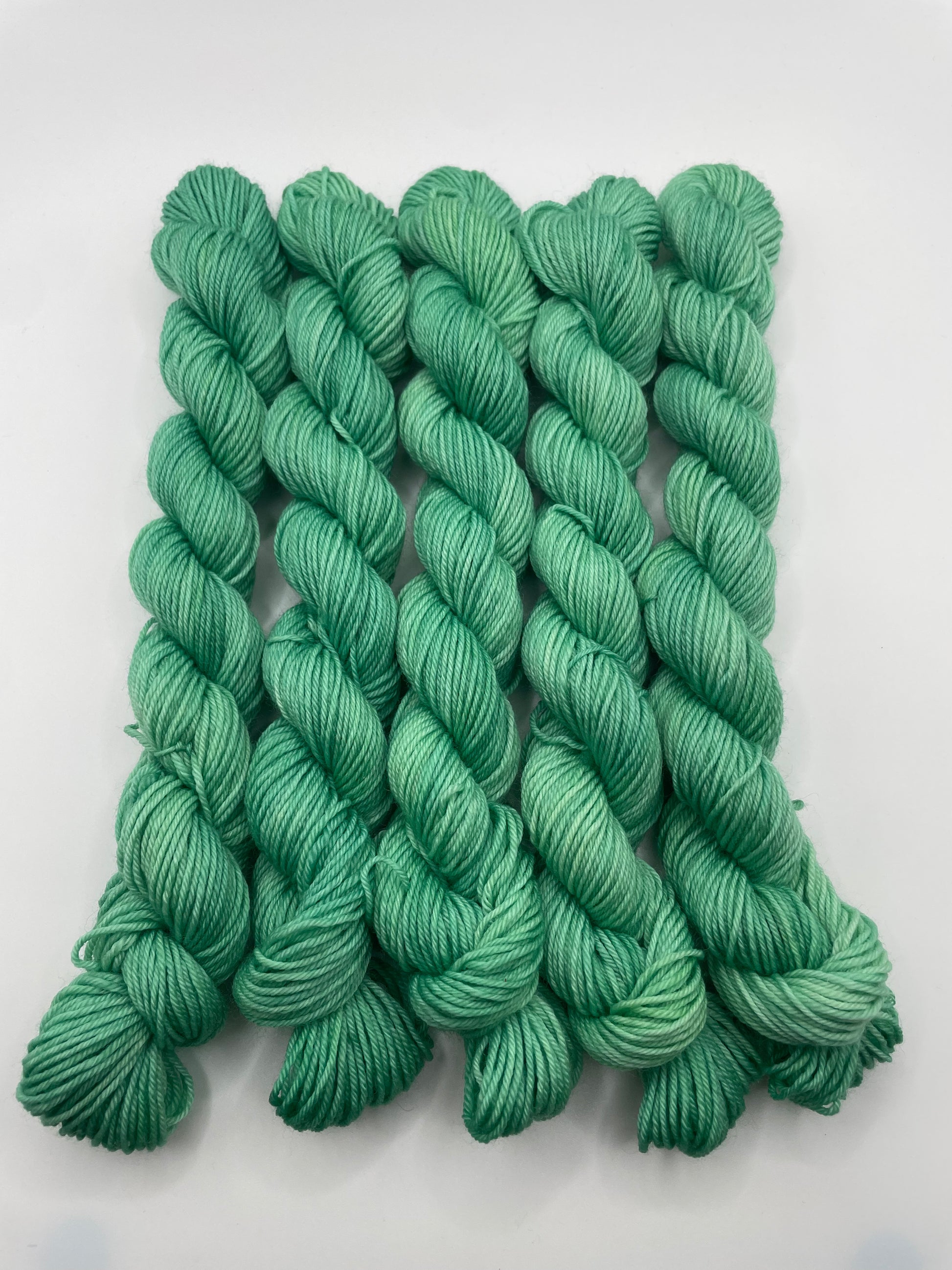 Green yarn mini skeins on a white background
