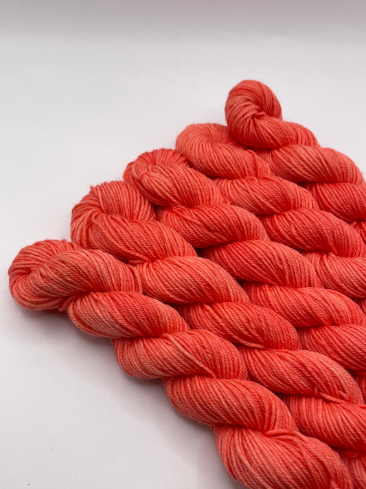 Orange red yarn mini skeins on a white background