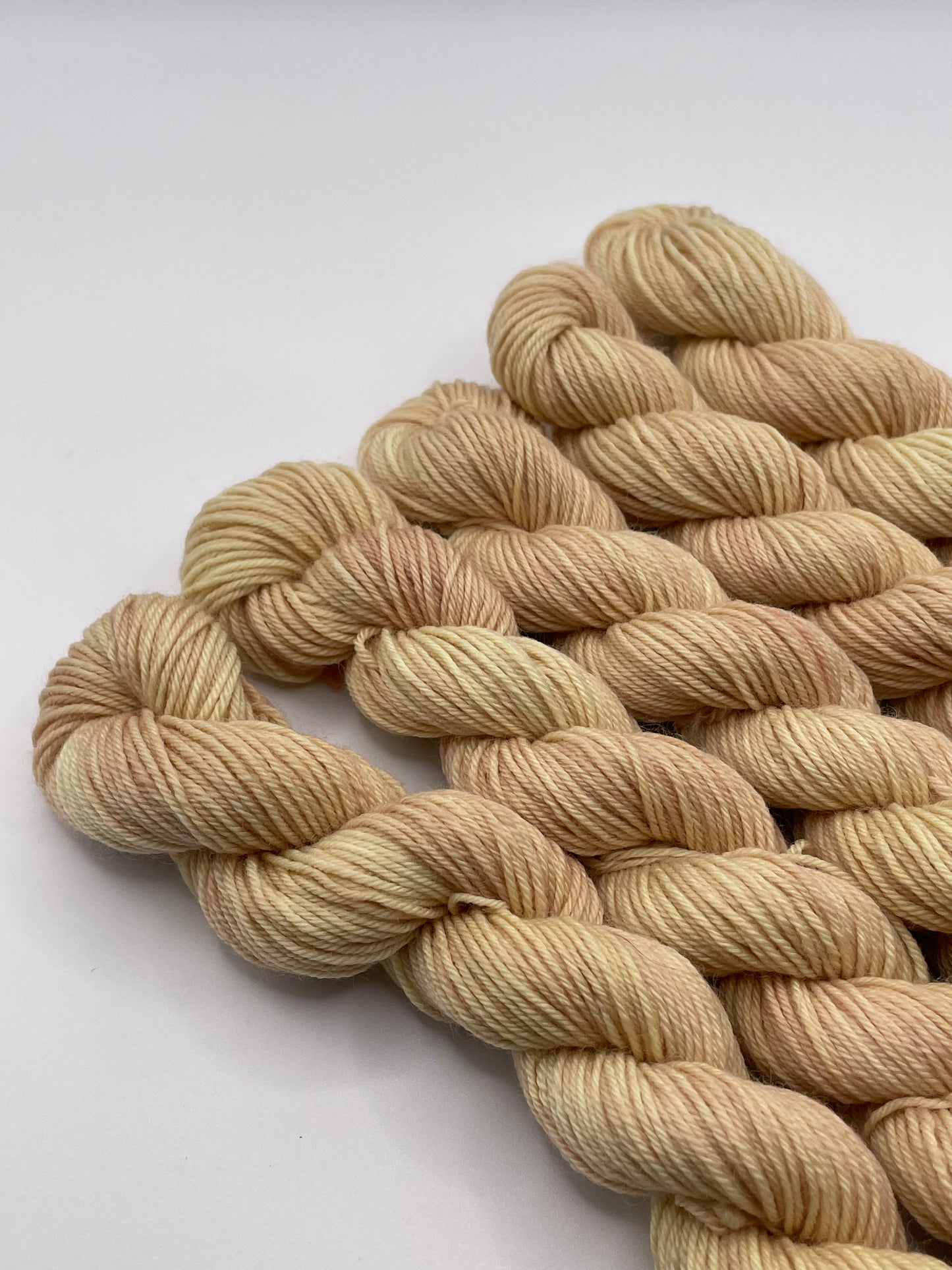 Creamy peach yarn mini skeins on a white background